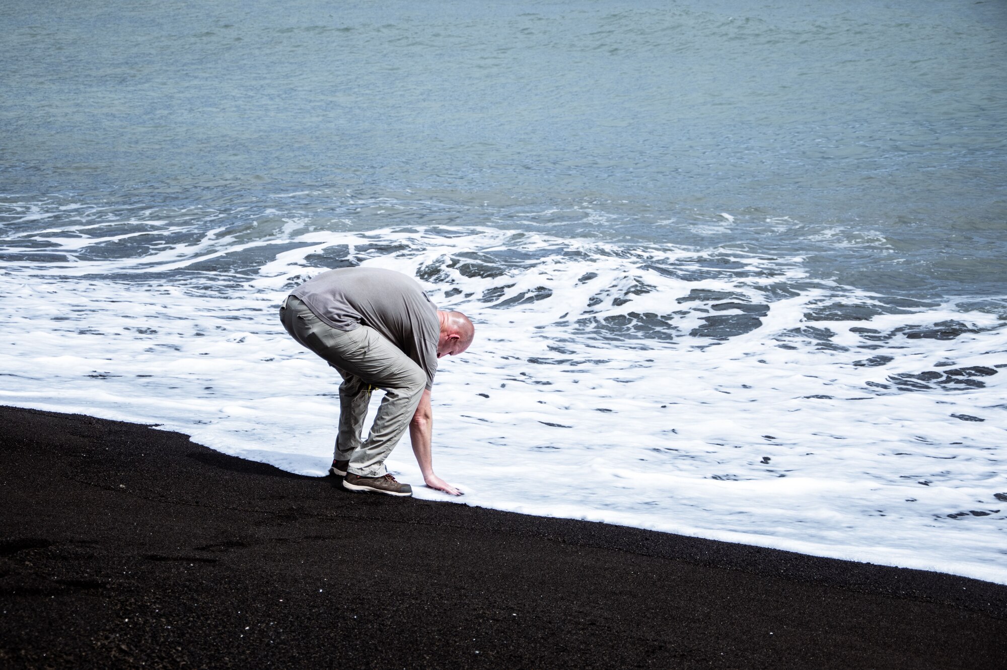 A Marine touches water at a beach.