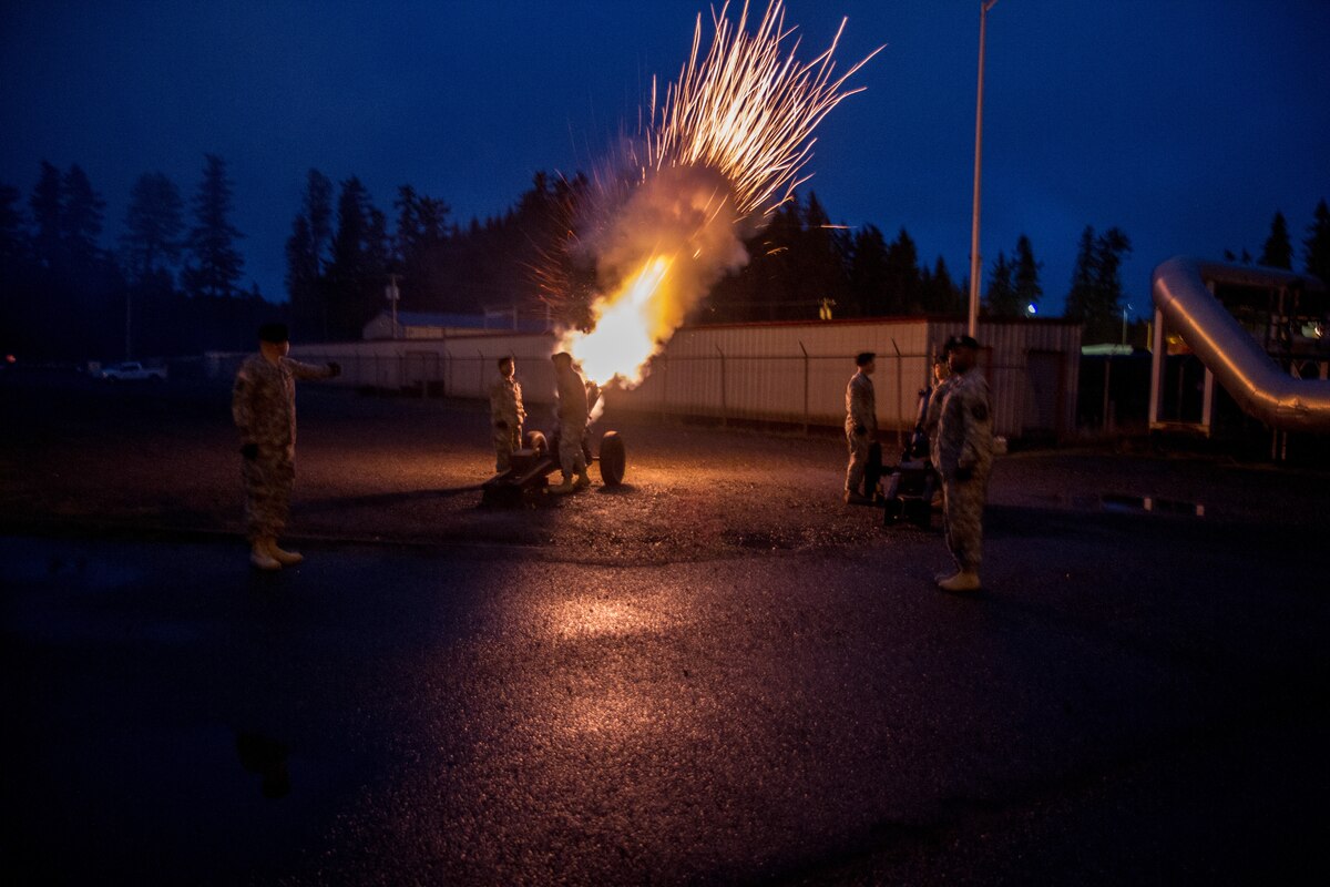 A large gun fires at night.