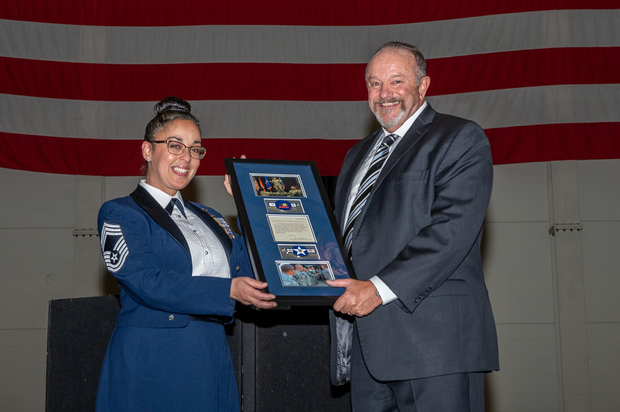 Two individuals holding a plaque.