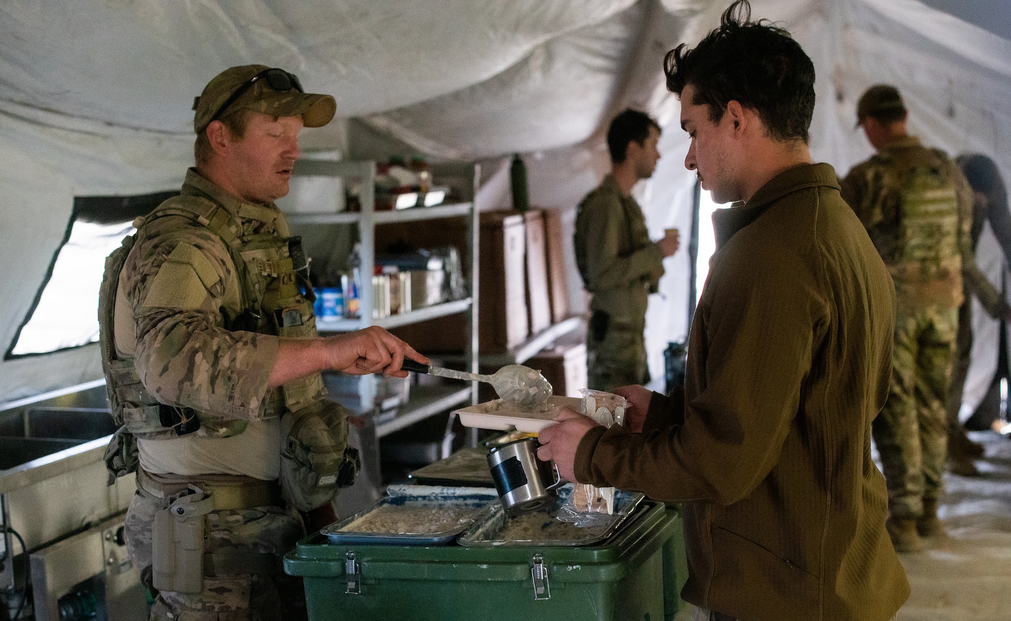 U.S. Air Force Staff Sgt. Tyler Kochlany, 27th Special Operations Civil Engineer Squadron explosive ordnance disposal technician, serves breakfast to Senior Airman Mark Anderson, 27th Special Operations Communications Squadron communications technician, during the Full Mission Profile 22-3 exercise at Sierra Blanca Regional Airport, New Mexico. (U.S. Air Force photo by Senior Airman Christopher Storer)