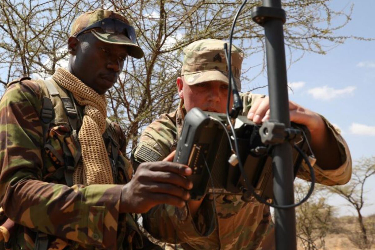 Two soldiers work together with survey equipment.