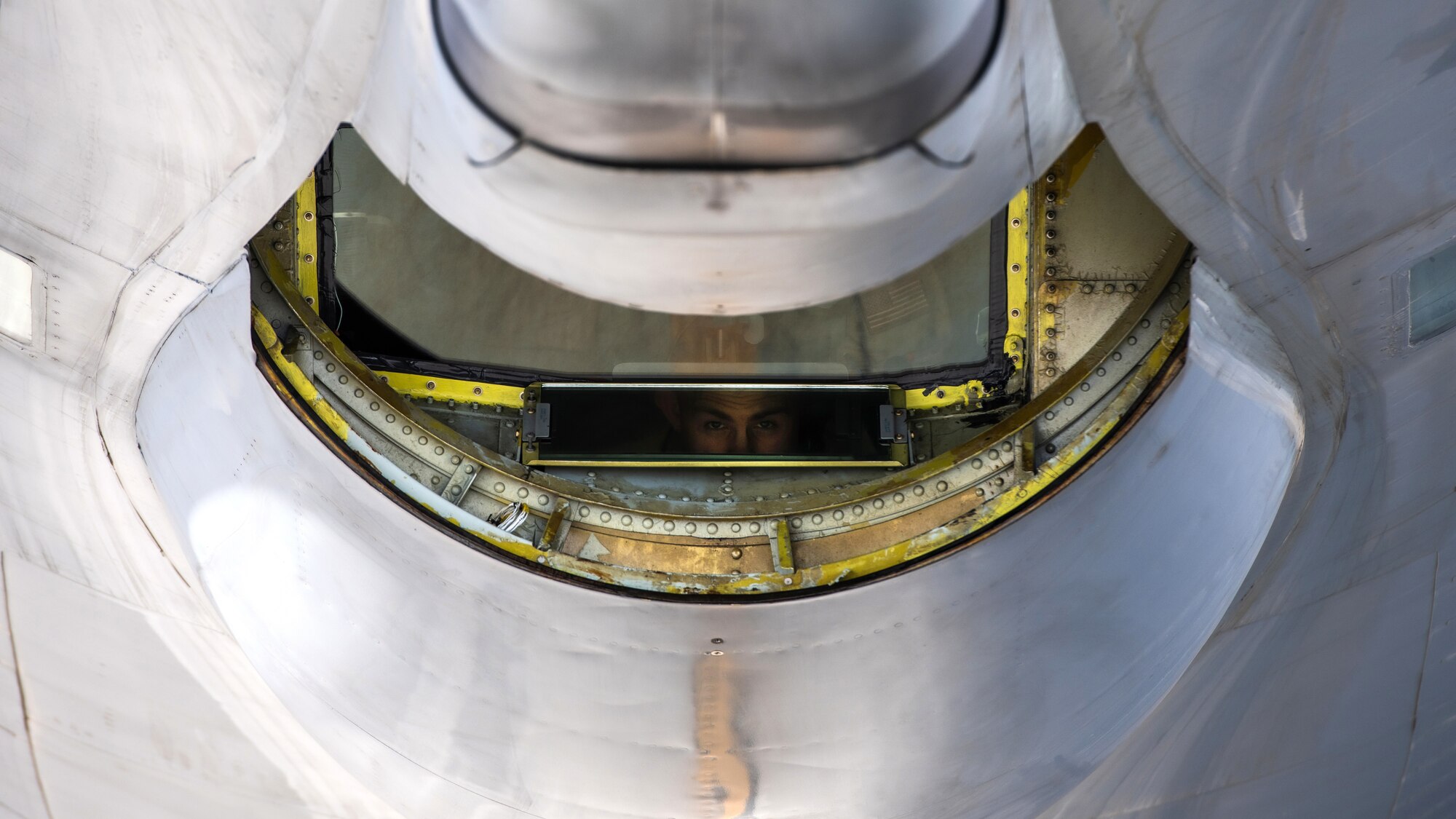 A U.S. Air Force boom operator looks through the rear window of a KC-135 Stratotanker