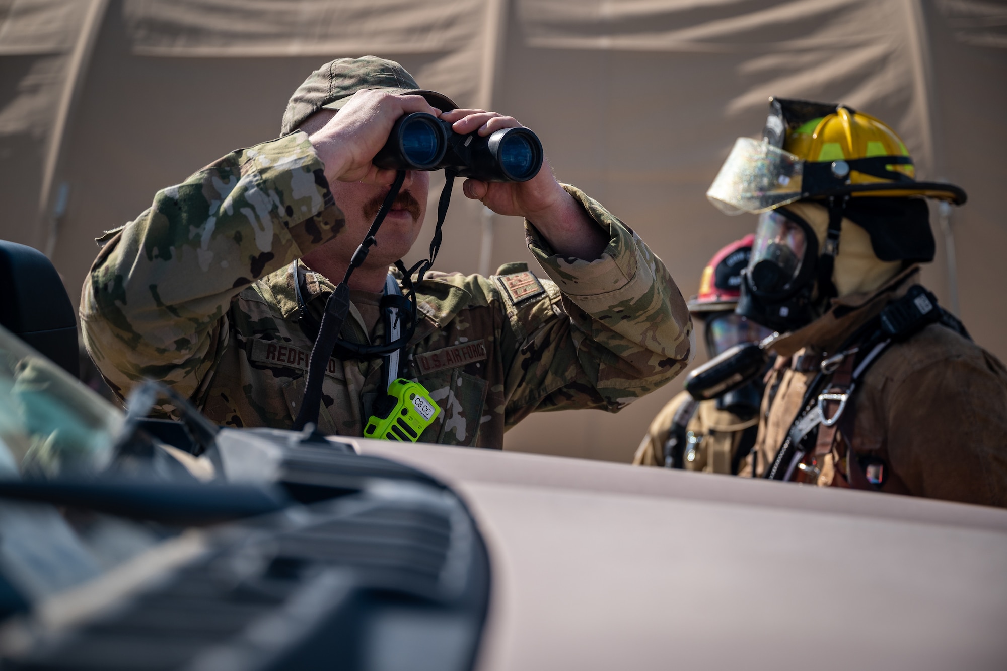 Tech Sgt. John Redfield, 332d Expeditionary Civil Engineer Squadron, emergency management incident commander, uses binoculars to better identify what type of hazardous material he and his team are up against during a hazardous materials training exercise at an undisclosed location in Southwest Asia March 24, 2022. Firefighters and emergency management technicians worked together during the hazardous materials exercise to isolate and secure hazardous materials as well as set up a decontamination line. (U.S. Air Force photo by Master Sgt. Christopher Parr)