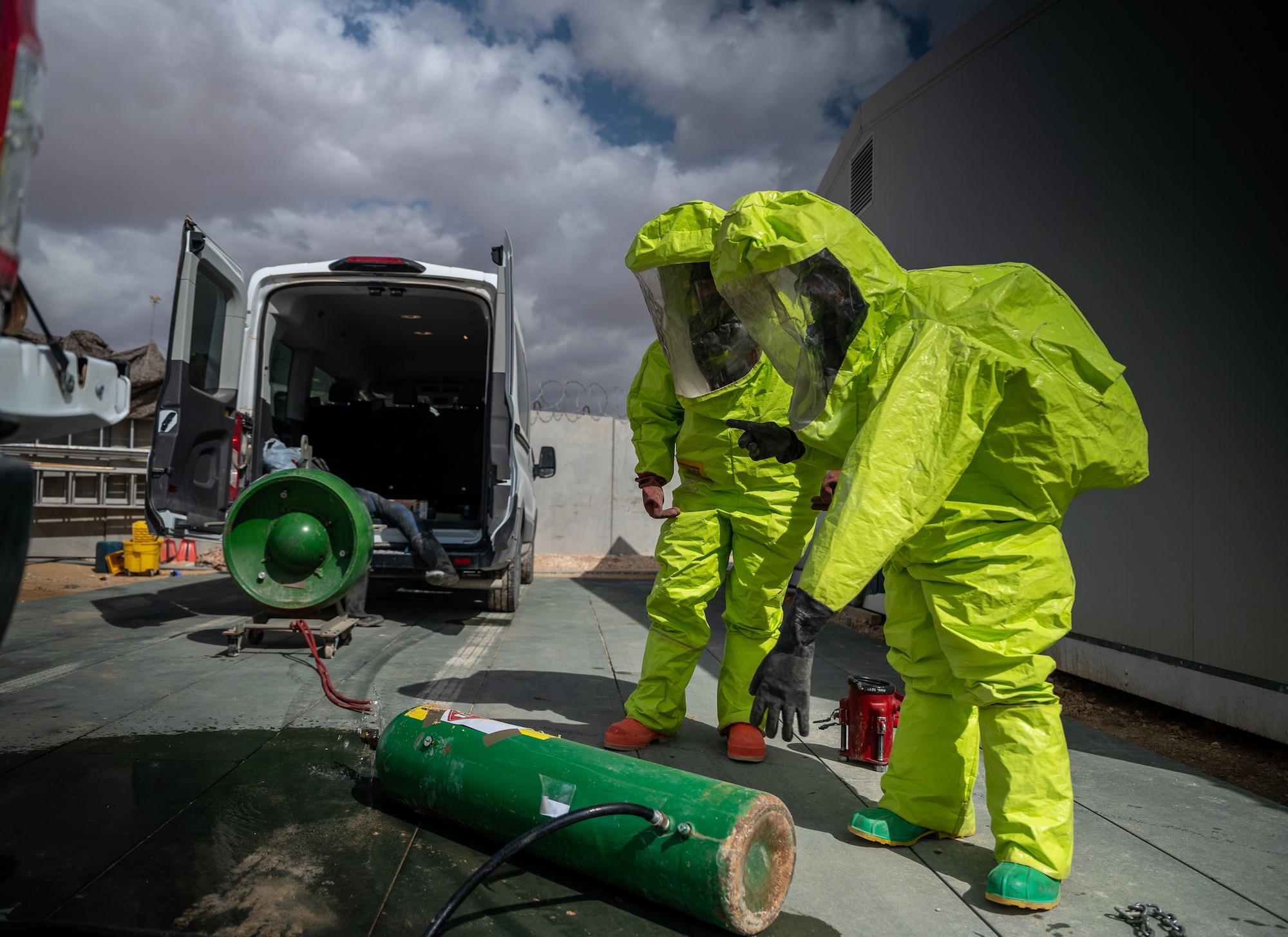 Senior Airman Katrina Brzeskiewicz and Airman First Class Parker Thomas, 332d Expeditionary Civil Engineer Squadron firefighters, wear level-A suits while they determine the type of hazardous material leaking from a container and how to best contain it from further leaking during a hazardous material exercise at an undisclosed location in Southwest Asia March 24, 2022.  Various cylinders represent the common containers that a HazMat tech might come upon and be required to evaluate, control, and stop leaking. (U.S. Air Force photo by Master Sgt. Christopher Parr)