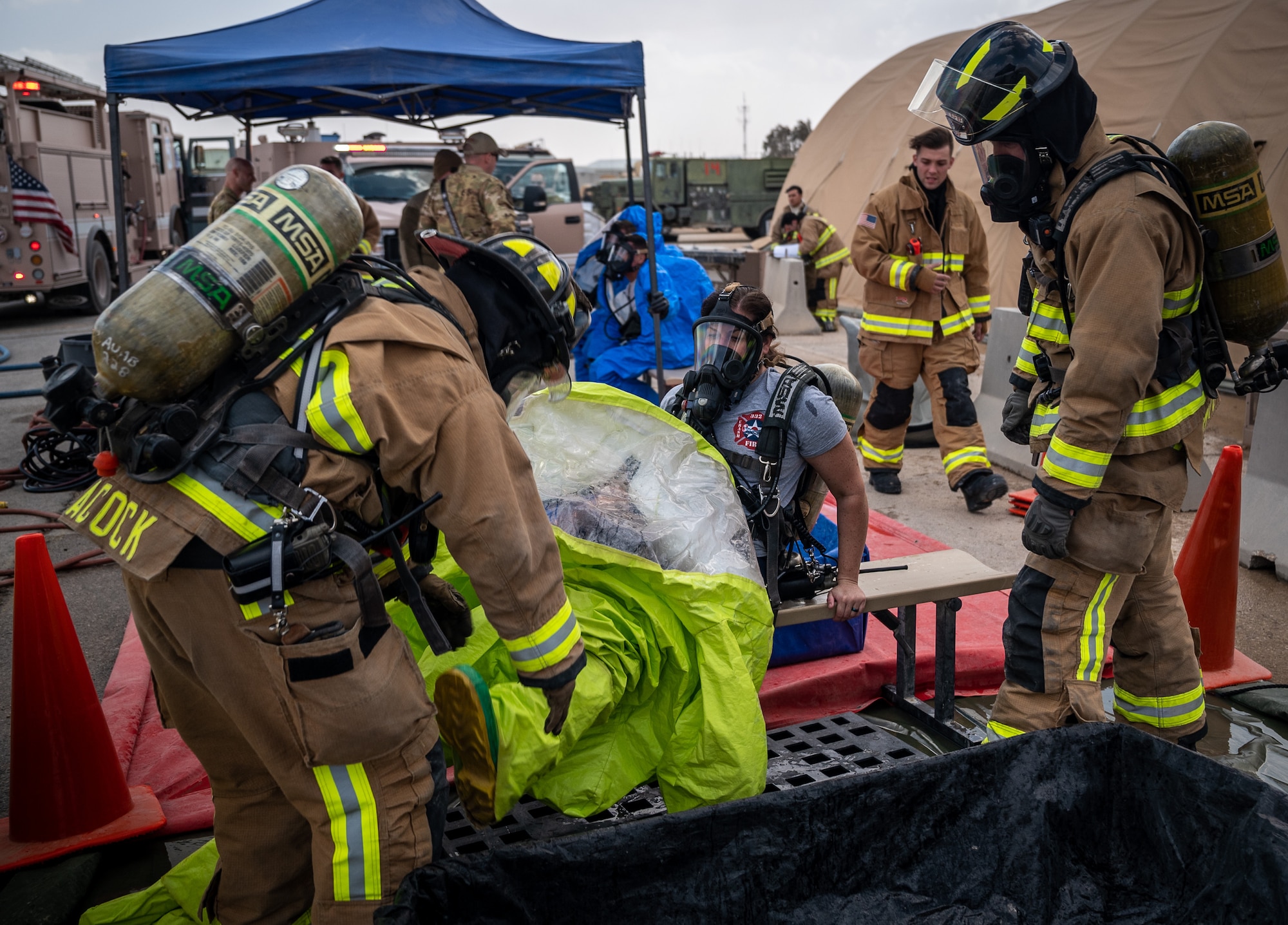 Senior Airman Katrina Brzeskiewicz, 332d Expeditionary Civil Engineer Squadron firefighter, receives assistance from fellow firefighters to carefully remove her protective gear and maintain the integrity of the clean area of the decontamination process during a hazardous material exercise at an undisclosed location in Southwest Asia March 24, 2022. Ensuring any potentially hazardous material is removed helps to keep the clean area, cold zone, free of contamination. (U.S. Air Force photo by Master Sgt. Christopher Parr)