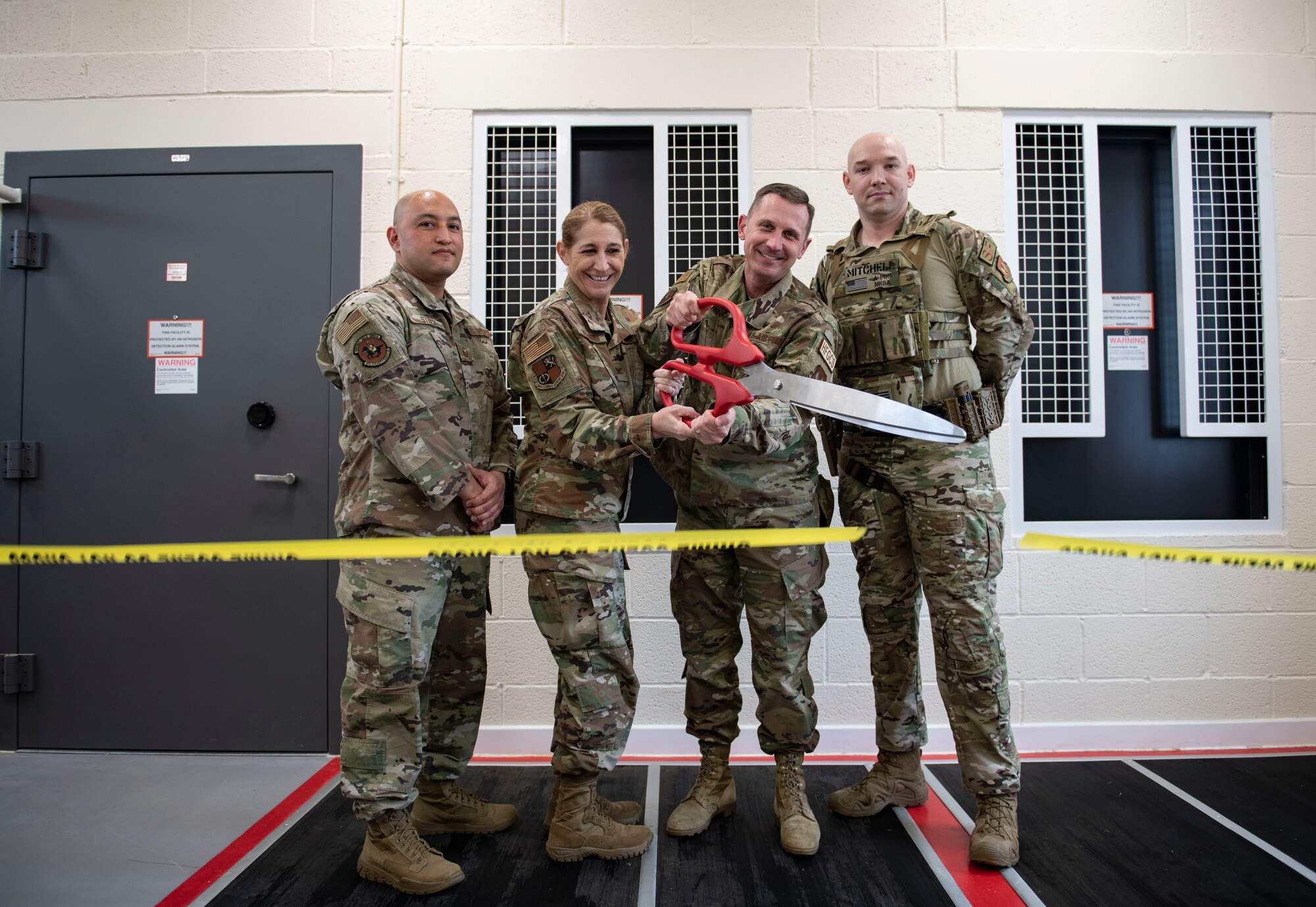 U.S. Air Force Col. Lisa M. Wildman, center-left, 501st Combat Support Wing vice commander, and Col. Jon T. Hannah, center-right, 422d Air Base Group commander, cut a ribbon to commemorate the opening of the new armory at RAF Croughton, England, April 6, 2022. The armory was the first in the entire Air Force to fully integrate a radio frequency identification tracking system. (U.S. Air Force photo by Senior Airman Jason W. Cochran)
