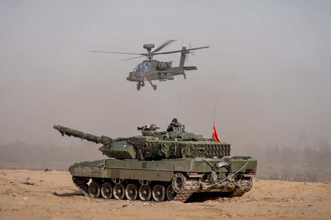 A helicopter flies above a tank.