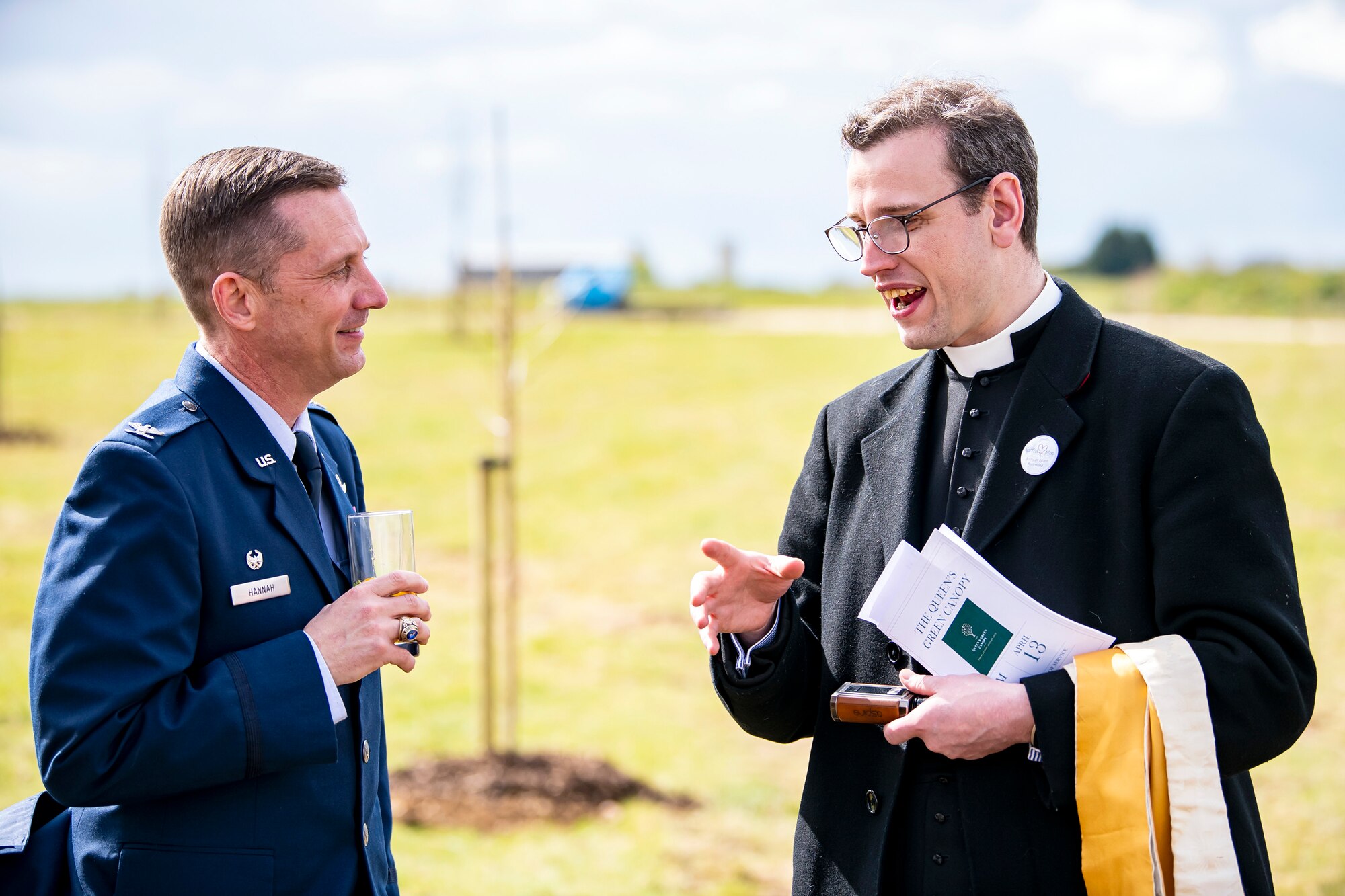 U.S. Air Force Col. Jon T. Hannah, left, 422d Air Base Group commander, speaks with Father Oliver Coss, Rector of All Saints’ Church, Northampton, prior to the Queen’s Green Canopy event at RAF Croughton, England, April 13, 2022. The event celebrated the Queen’s Platinum Jubilee initiative, marking the 70th year of her reign. During the event, trees were planted to create a legacy in honor of the queen’s leadership of the nation. (U.S. Air Force photo by Staff Sgt. Eugene Oliver)