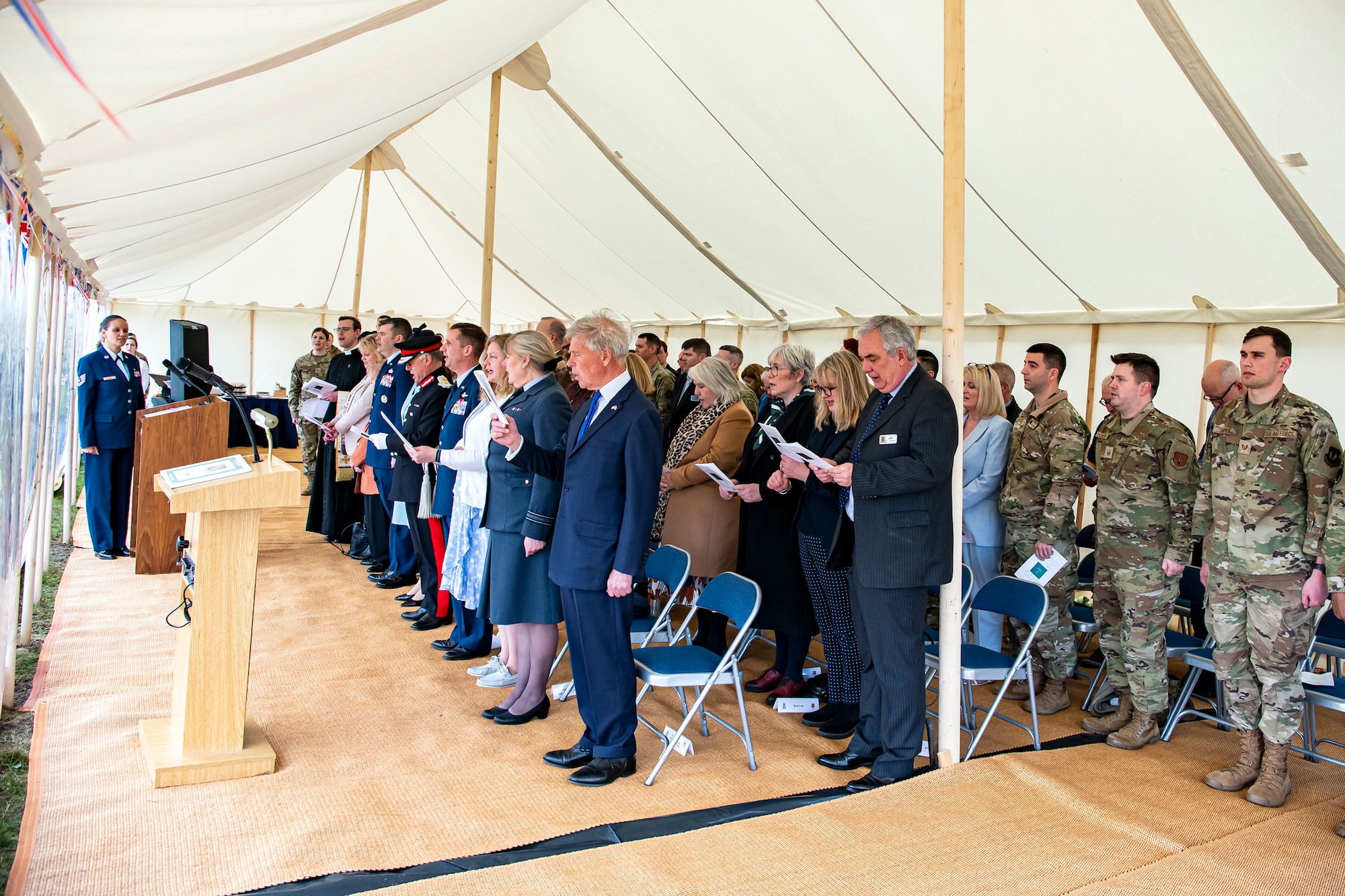 Distinguished guests and Airmen from the 501st Combat Support Wing sing the national anthem at the conclusion of the Queen’s Green Canopy event at RAF Croughton, England, April 13, 2022. The event celebrated the Queen’s Platinum Jubilee initiative, marking the 70th year of her reign. During the event, trees were planted to create a legacy in honor of the queen’s leadership of the nation. (U.S. Air Force photo by Staff Sgt. Eugene Oliver)