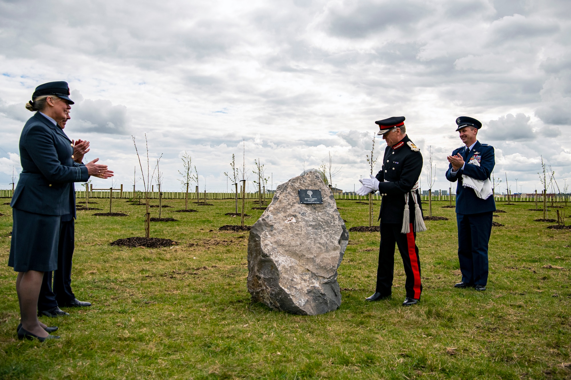 U.S. Air Force Col. Jon T. Hannah, right, 422d Air Base Group commander, James Saunders-Watson, center right, Lord-Lieutenant of Northamptonshire and other distinguished guests applaud after the unveiling of a stone commemorating the Queen’s Green Canopy event at RAF Croughton, England, April 13, 2022. The event celebrated the Queen’s Platinum Jubilee initiative, marking the 70th year of her reign. During the event, trees were planted to create a legacy in honor of the queen’s leadership of the nation. (U.S. Air Force photo by Staff Sgt. Eugene Oliver)