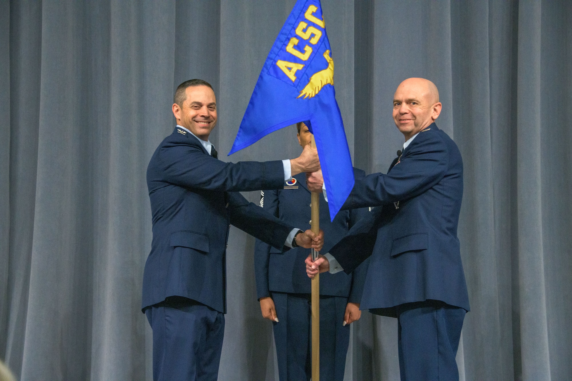 Colonel Lee Gentile (left), commandant of Air Command and Staff College, hands the unit flag for the newly activated Global College of PME to Col. Craig Ramsey during an activation and assumption of command ceremony April 1, 2022, Maxwell Air Force Base, Ala. Ramsey serves as the first commandant of the college, which falls under ACSC and is responsible for providing online professional military education courses to more than 30,000 students.