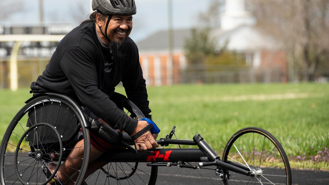 An RSM smiles from his wheelchair racer during track practice.