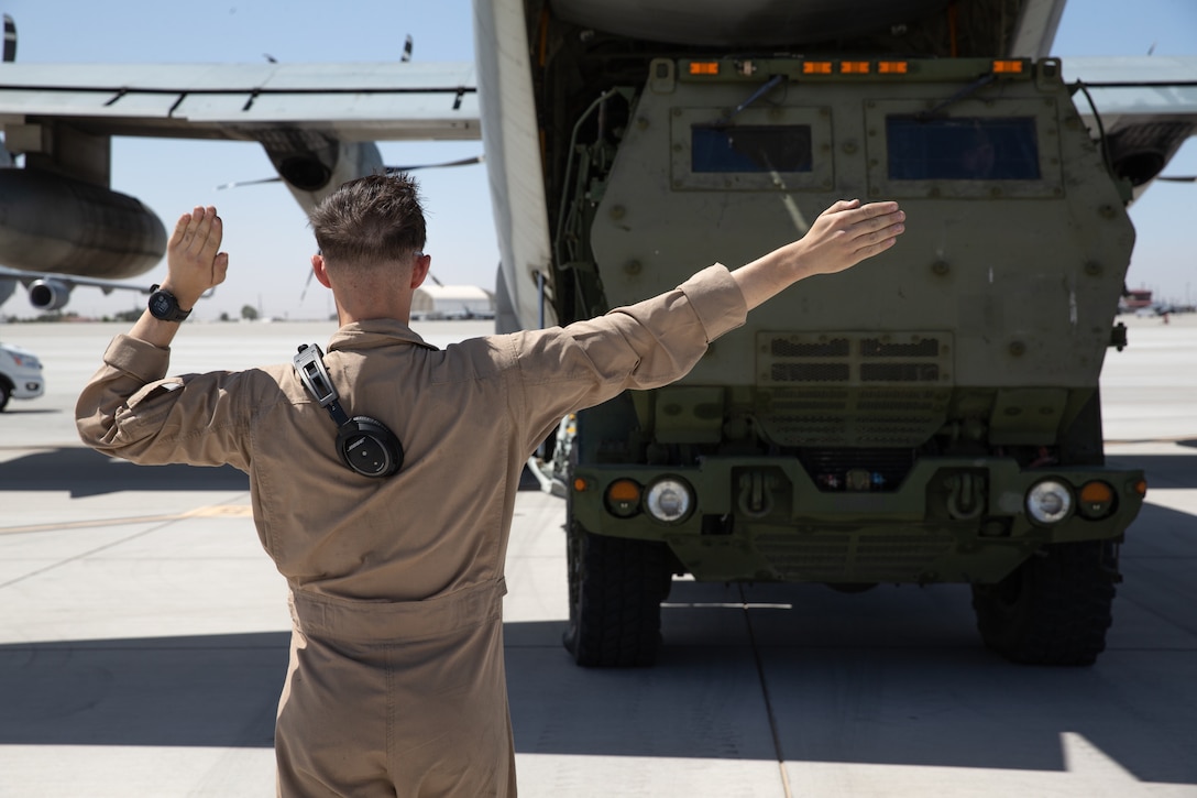 A U.S. Marine with Marine Aerial Refueler Transport Squadron 152, 1st Marine Aircraft Wing, directs an M142 High Mobility Artillery Rocket System assigned to Kilo Battery, 2nd Battalion, 14th Marine Regiment, Marine Forces Reserve, while conducting a HIMARS rapid insertion training event during Weapons and Tactics Instructor course 2-22 at Marine Corps Air Station Yuma, Ariz., April 6, 2022. The Marine Corps utilizes HIMARS and its KC-130J aircraft to provide combatant commanders with rapidly deployable precision fires asset, capable of being anywhere in the world within 24 hours.