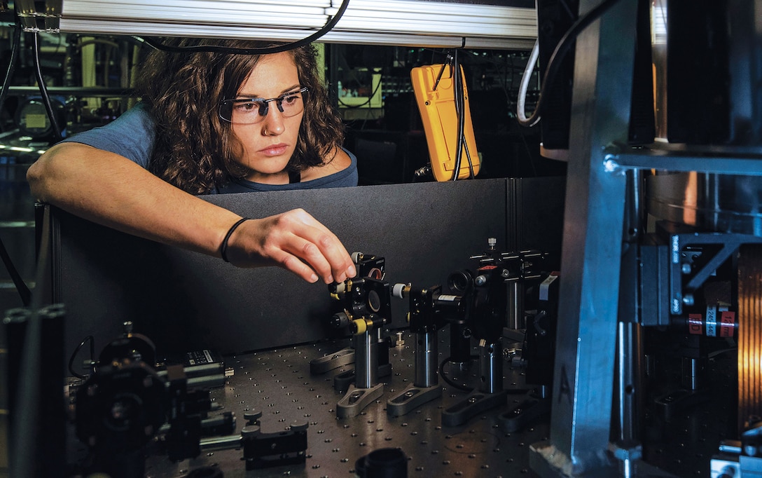 National Institute of Standards and Technology physicist Katie McCormick adjusts mirror to steer laser beam used to cool trapped beryllium ion, as part of efforts to improve quantum measurements and quantum computing.