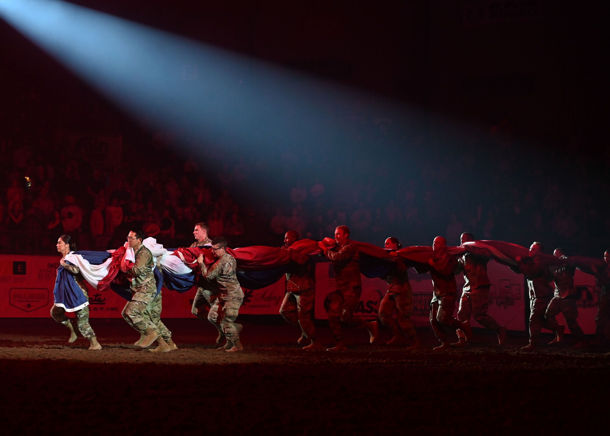 Service members from Goodfellow Air Force Base carry the American flag to the center of the ring during the San Angelo Stock Show and Rodeo’s Military Appreciation Night at the Foster Communications Coliseum, April 13, 2022. Goodfellow members unfurl the flag as a prelude to the singing of the National Anthem. (U.S. Air Force photo by Airman 1st Class Sarah Williams)