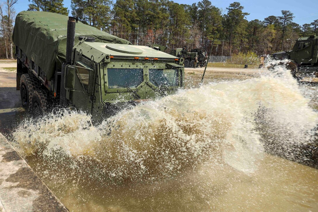 A military vehicle drives through water.