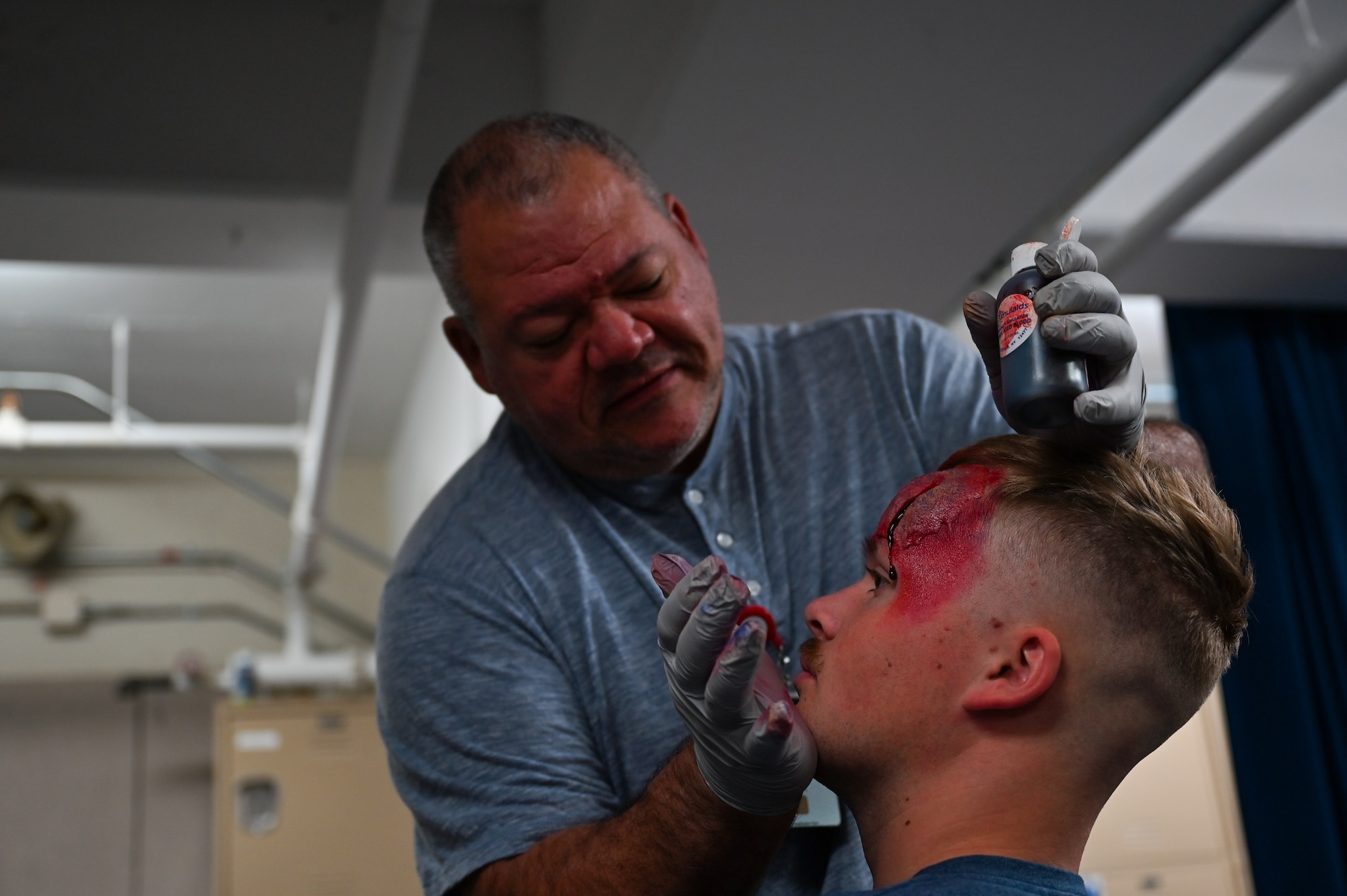 Brian Dry, 22nd Medical Group flight medical technician, applies makeup and fake blood to Airman Alexander Johnson, 22nd Security Forces Squadron entry controller, during exercise Ready Eagle April 8, 2022 at McConnell Air Force Base, Kansas.