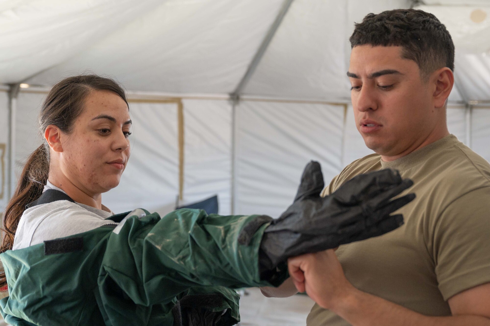 Staff Sgt. Candelaria Flores dons her chemical warfare ensemble with the assistance of Staff Sgt. Sergio Cano during an in-person combined training event with other Air and Army National Guard units this week in Las Vegas. Both are FSS Specialists who have volunteered for the 162nd FSS FSRT mission.