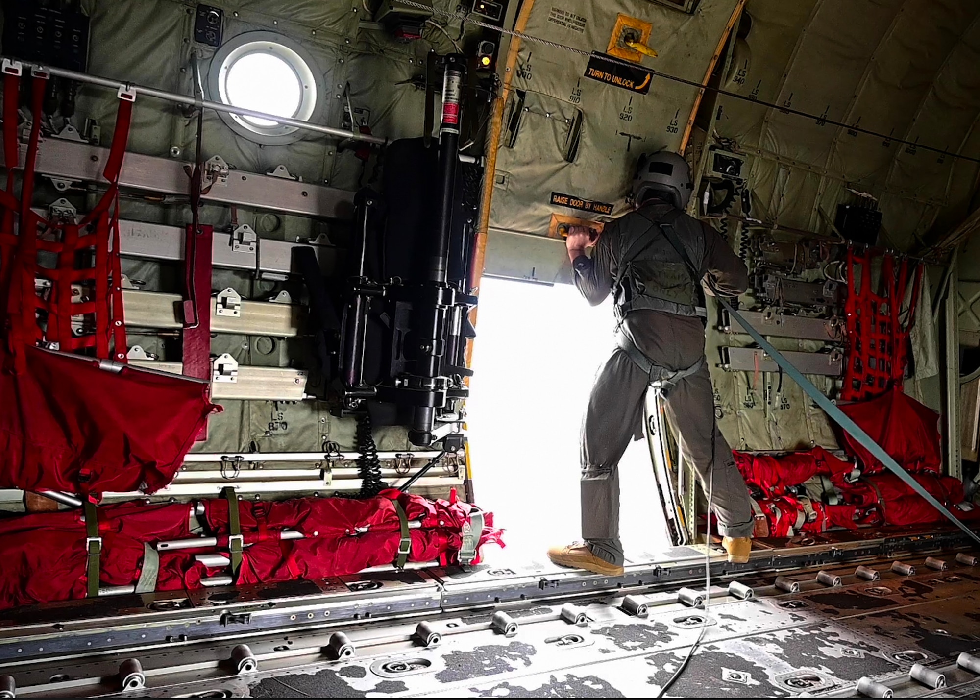 A loadmaster from the 29th Weapons Squadron opens a paratrooper door on a C-130J Super Hercules