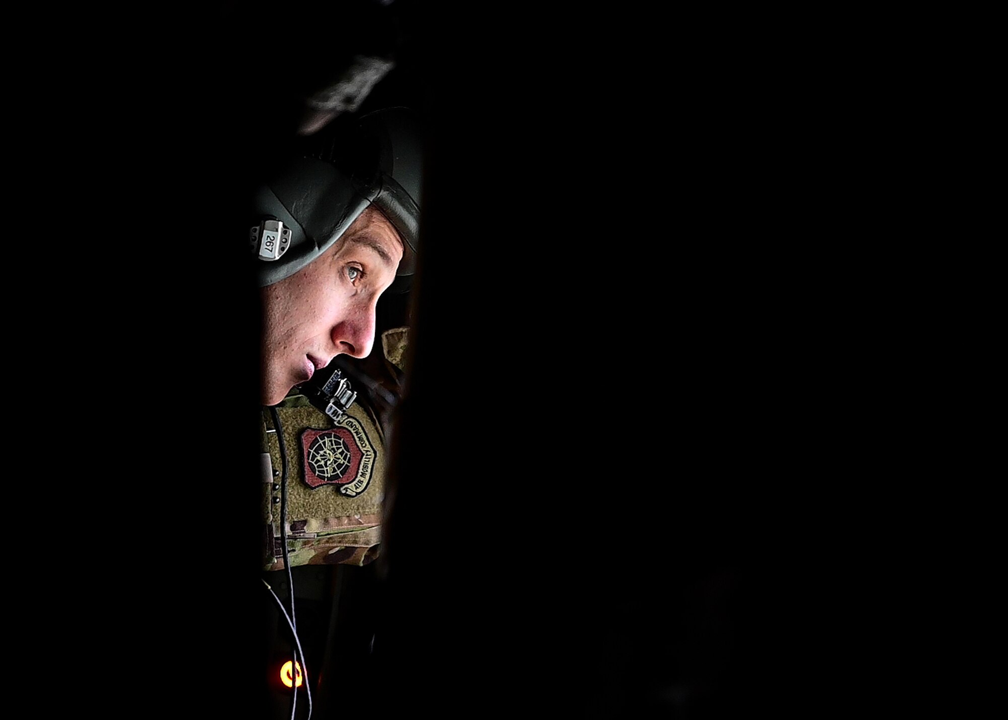 A loadmaster from the 29th Weapons Squadron looks out of the window of a C-130J Super Hercules