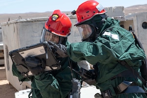 Staff Sgt. Candelaria Flores dons her chemical warfare ensemble with the assistance of Staff Sgt. Sergio Cano during an in-person combined training event with other Air and Army National Guard units this week in Las Vegas. Both are FSS Specialists who have volunteered for the 162nd FSS FSRT mission.