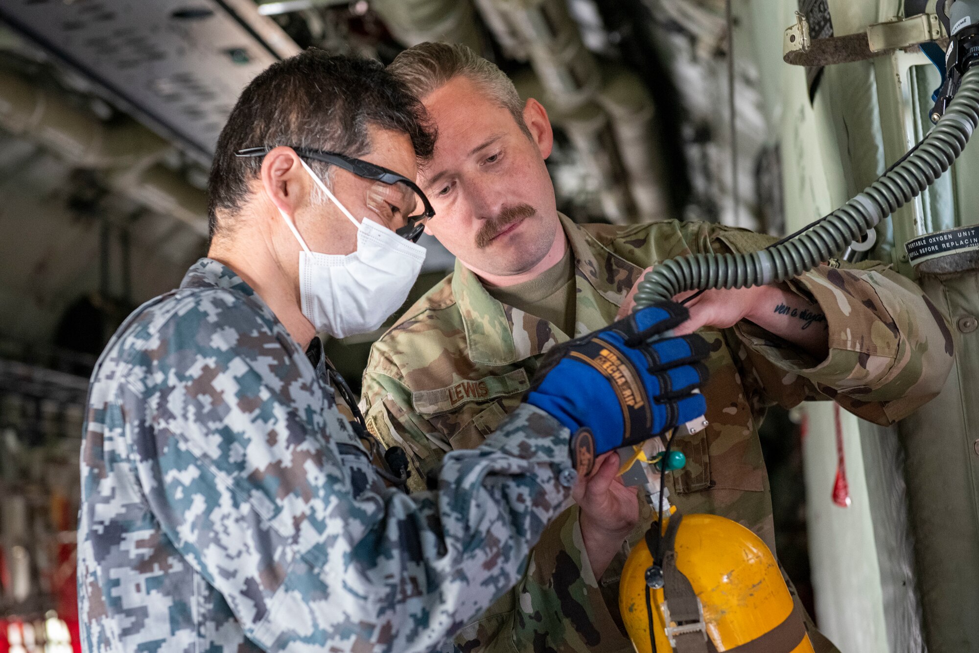 A U.S. Air Force Airman demonstrates how the U.S. Air Force performs inspections inside a C-130J Super Hercules to a Japan Air Self-Defense Force member
