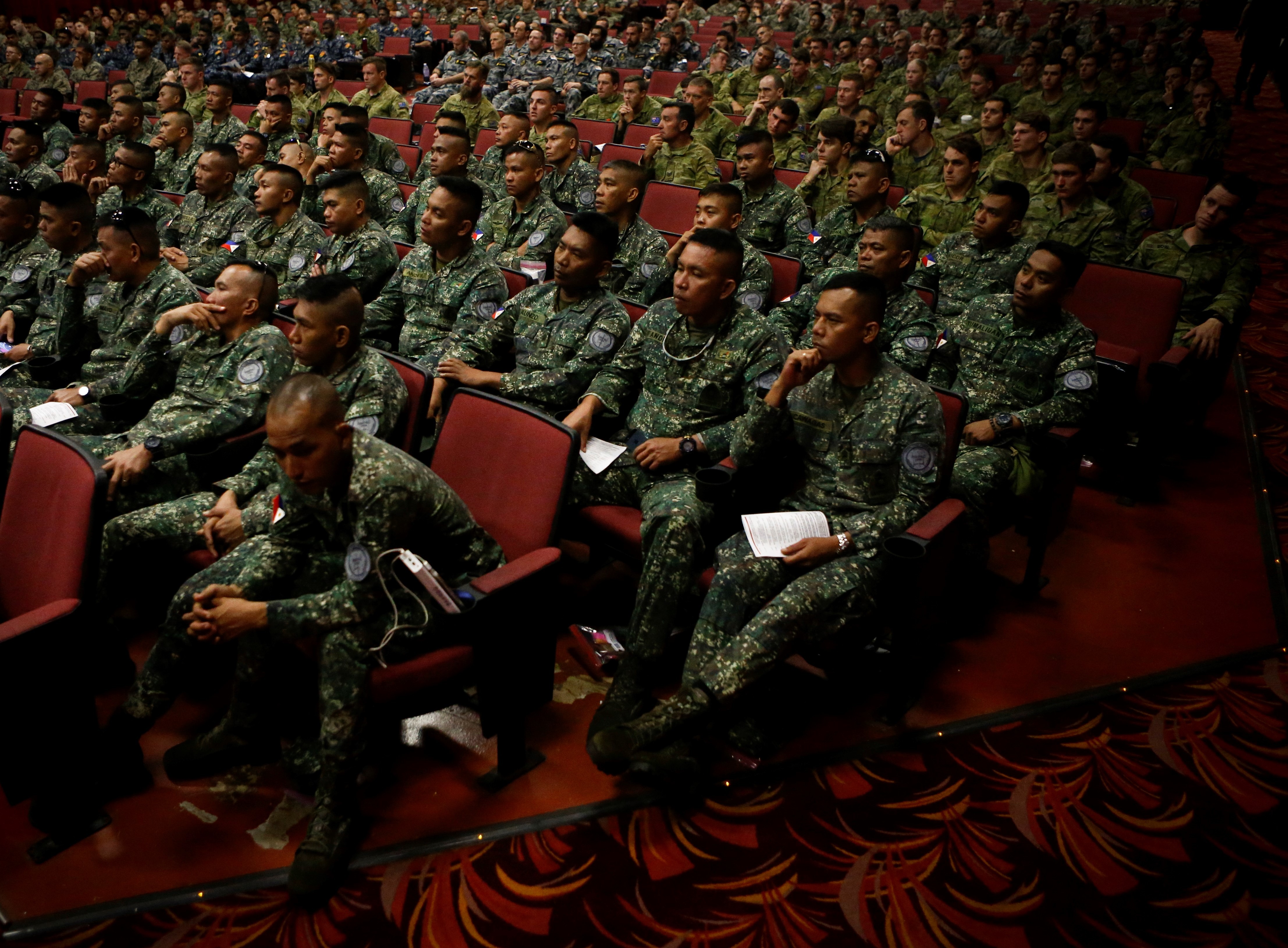 Many Marines sitting in an dimly lit auditorium.