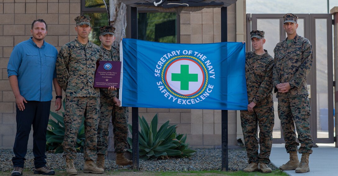 Marines posing with a blue flag outside a building.