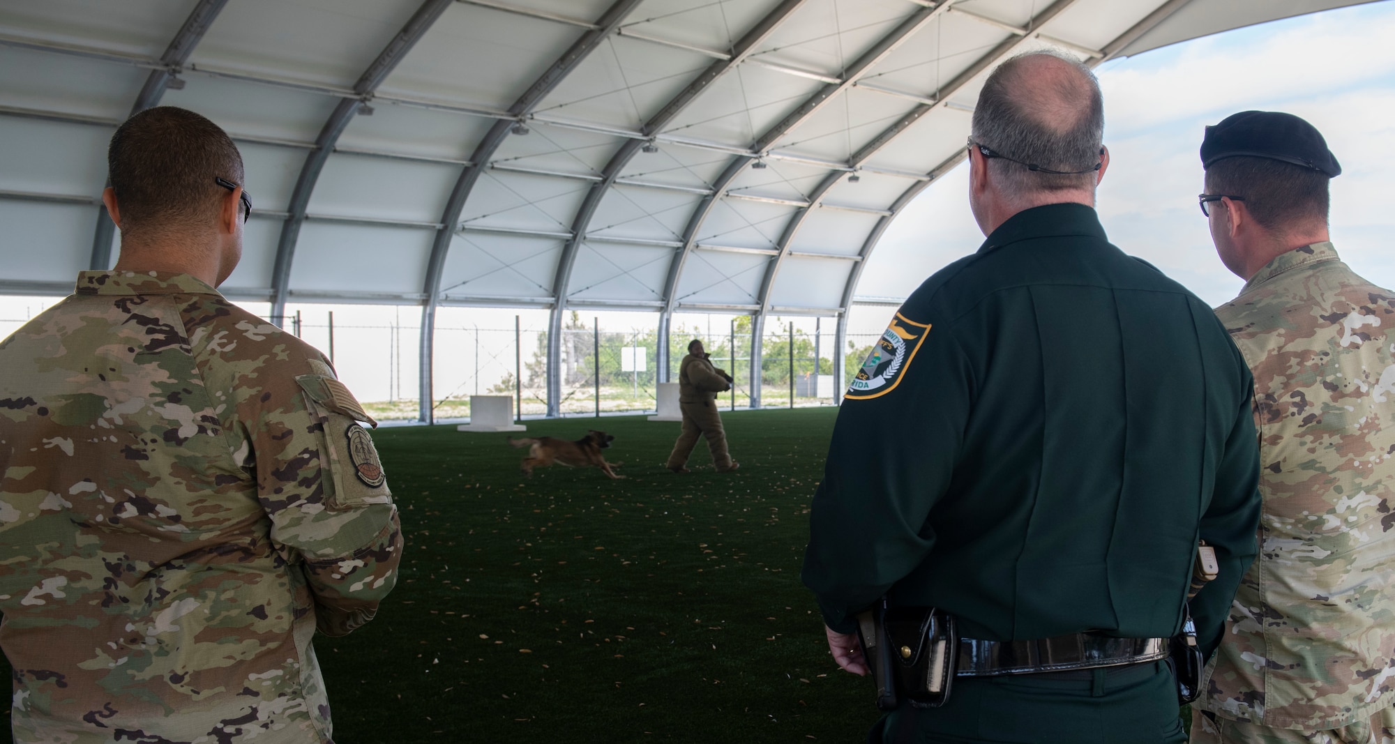 From left, U.S. Air Force Tech. Sgt. Marcus Lavalais, 325th Security Forces Squadron kennel master, Tommy Ford, 325th SFS honorary commander, and Maj. Jordan Criss, 325th SFS commander, observe as an Airman demonstrates bite tactics with a military working dog at Tyndall Air Force Base, Florida, April 13, 2022.