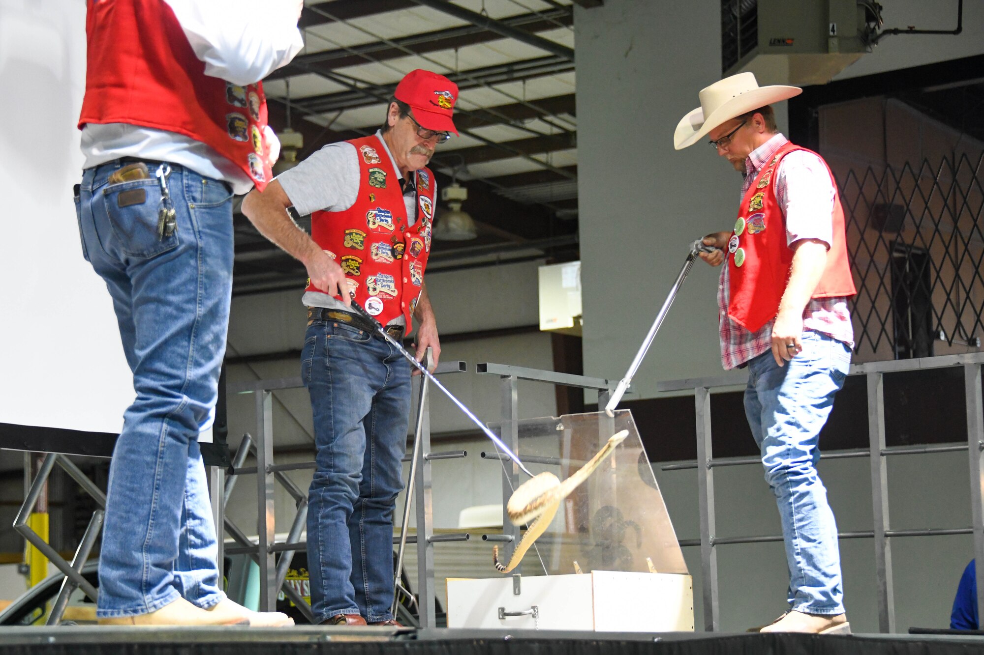Mangum Rattlesnake Derby members take out a rattlesnake to show audience members at the Committee of 100 dinner event in Altus, Oklahoma, April 11, 2022. The rattlesnake is one of the most populous species of snake living in the western half of Oklahoma. (U.S. Air Force photo by Senior Airman Kayla Christenson)