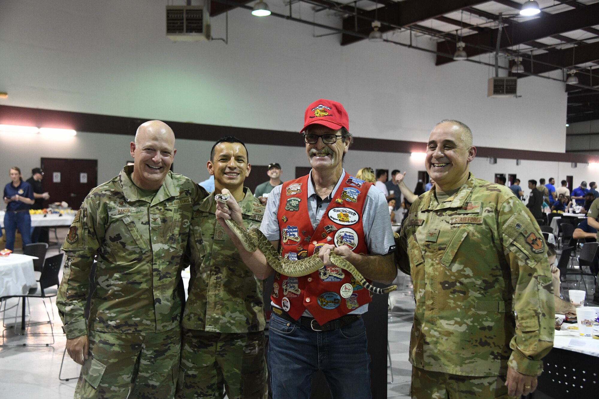 Leaders from the 97th Air Mobility Wing pose with a Mangum Rattlesnake Derby member at the Committee of 100 dinner event in Altus, Oklahoma, April 11, 2022. The Mangum Rattlesnake Derby is a part of the Shortgrass Rattlesnake Association in Mangum, Oklahoma. (U.S. Air Force photo by Senior Airman Kayla Christenson)