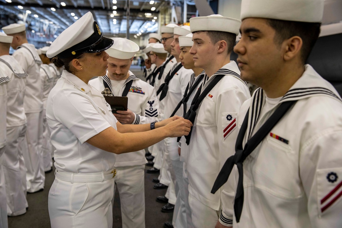 Sailors line up to take part in a uniform inspection.
