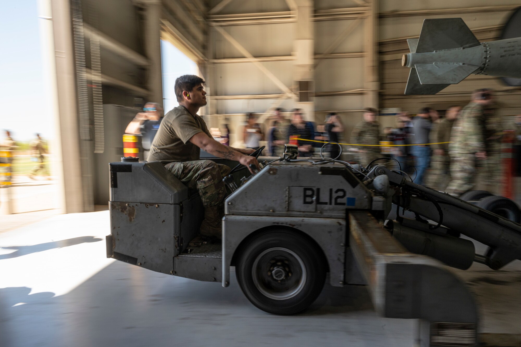 Airman 1st Class Jose Tovar, 7th Aircraft Maintenance Unit weapons load crew member, loads an inert bomb onto a B-1B Lancer during a Load of the Quarter competition at Dyess Air Force Base, Texas, April 14, 2022. The B-1 carries the largest conventional payload of both guided and unguided munitions, making the strategic bomber capable of rapidly delivering massive quantities of precision and non-precision weapons around the globe. (U.S. Air Force photo by Senior Airman Colin Hollowell)