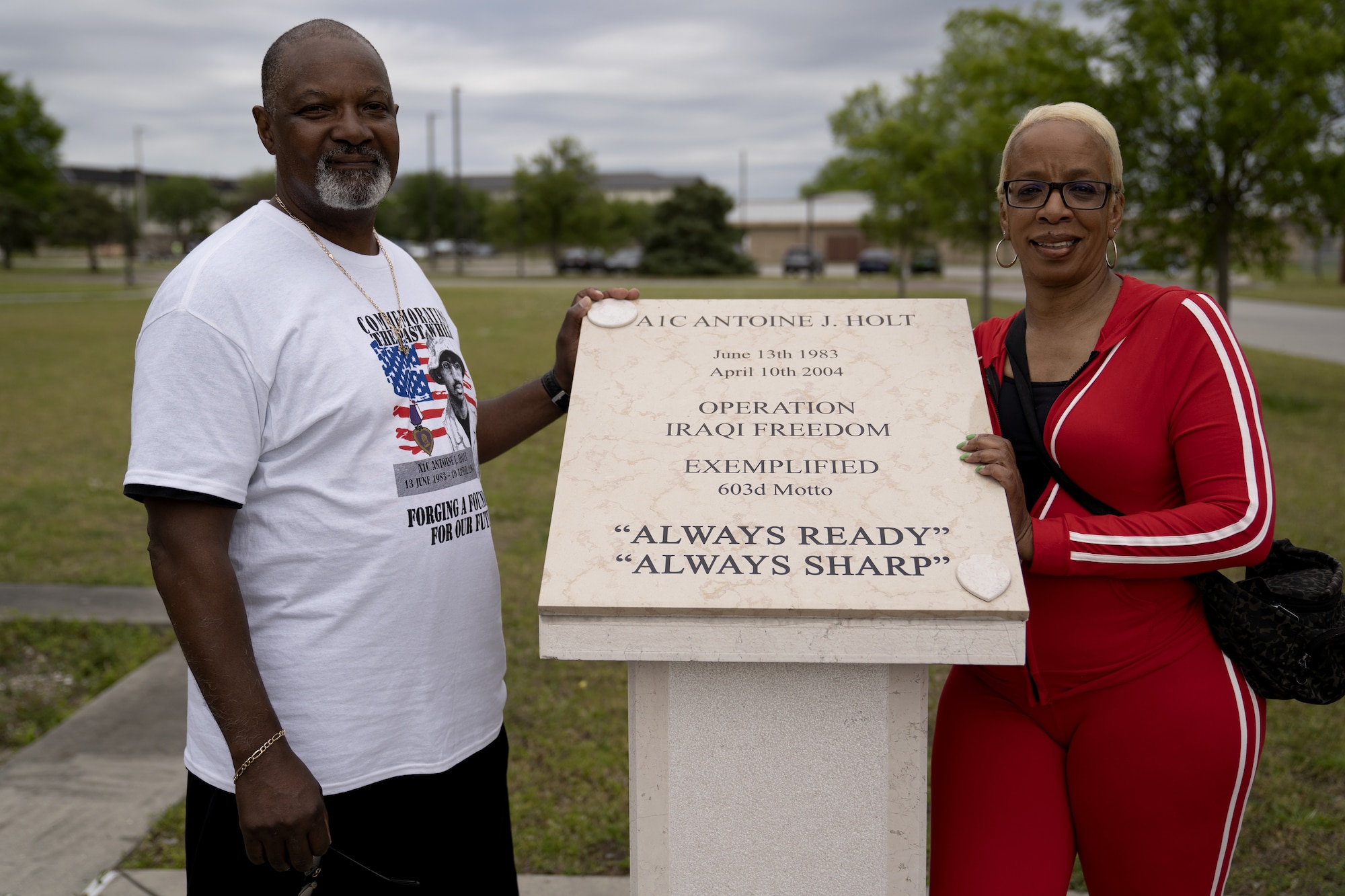 Michael Holt, U.S. Air Force Airman 1st Class Antoine Holt's father, and Shermain Holt, Antoine's mother, pose next to Antoine's memorial plaque at Avery Manor on Keesler Air Force Base, Mississippi, April 15, 2022. The Holt 5k Memorial run is an annual event to honor Antoine, 603rd Air Control Squadron command and control battle management operations operator, who died while serving in Iraq. (U.S. Air Force photo by Airman 1st Class Trenten Walters)