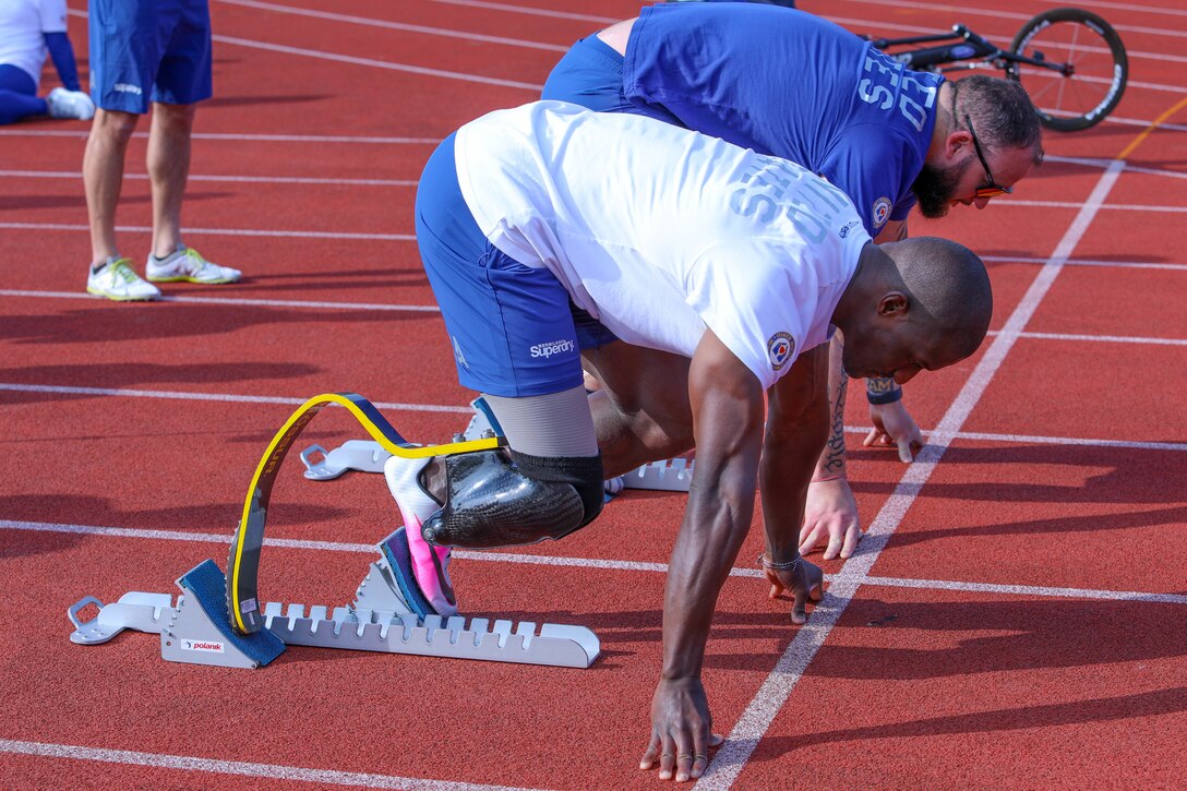 Two athletes assume the set position before a race on a track.
