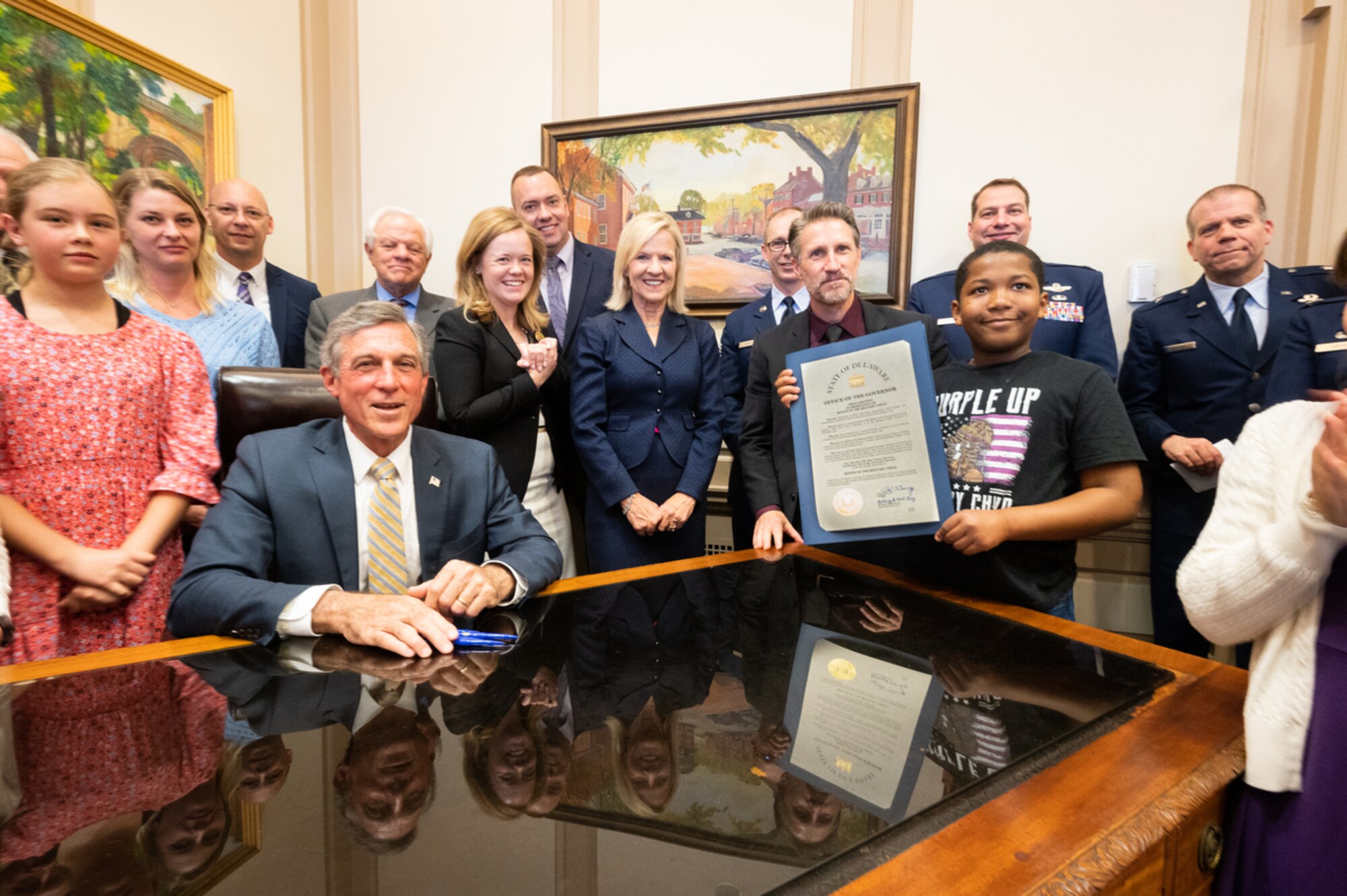 Team Dover leadership along with students and faculty from Major George S. Welch Elementary School stand with Delaware Gov. John Carney after signing a document proclaiming April as the Month of the Military Child in Dover, Delaware, April 12, 2022. The Month of the Military Child was established in 1986, recognizing the contributions and personal sacrifices children make to the armed forces. (U.S. Air Force photo by Mauricio Campino)