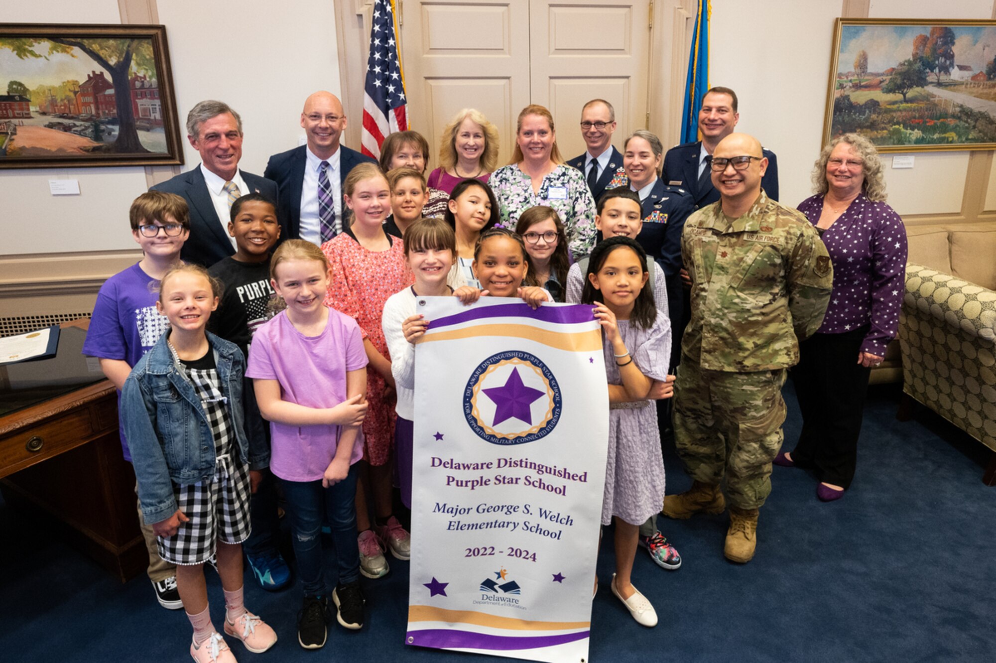 Team Dover leadership along with students and faculty from Major George S. Welch Elementary School stand with Delaware Gov. John Carney after signing a document proclaiming April as the Month of the Military Child in Dover, Delaware, April 12, 2022. The Month of the Military Child was established in 1986, recognizing the contributions and personal sacrifices children make to the armed forces. (U.S. Air Force photo by Mauricio Campino)
