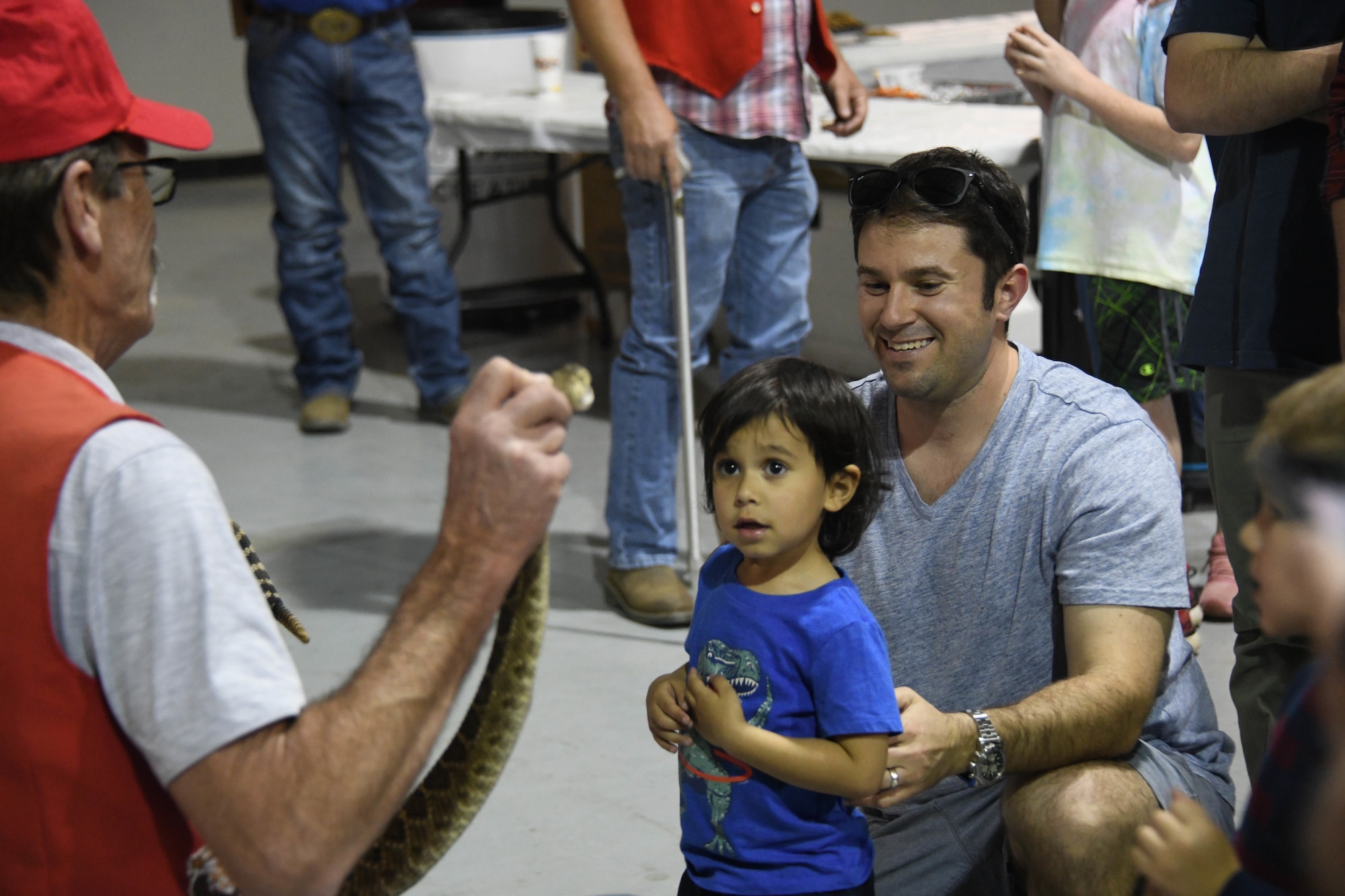 A child looks at a rattlesnake at the Committee of 100 dinner event in Altus, Oklahoma, April 11, 2022. More than 15 children attended the event to participate in bouncing houses, mechanical bull riding and the Mangum Rattlesnake Derby appearance. (U.S. Air Force photo by Senior Airman Kayla Christenson)