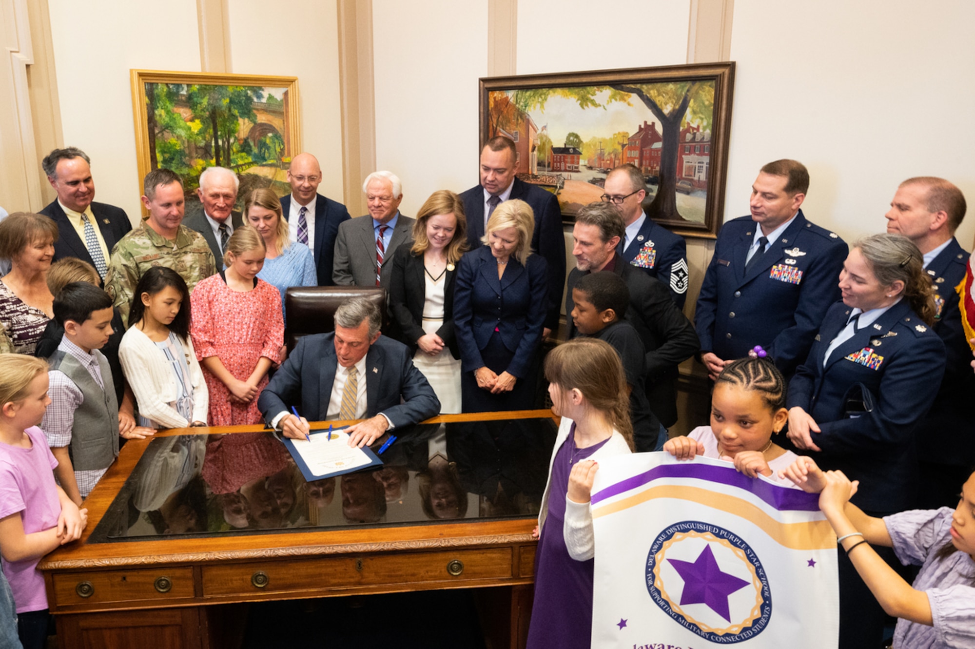 Team Dover leadership along with students and faculty from Major George S. Welch Elementary School stand with Delaware Gov. John Carney after signing a document proclaiming April as the Month of the Military Child in Dover, Delaware, April 12, 2022. The Month of the Military Child was established in 1986, recognizing the contributions and personal sacrifices children make to the armed forces. (U.S. Air Force photo by Mauricio Campino)