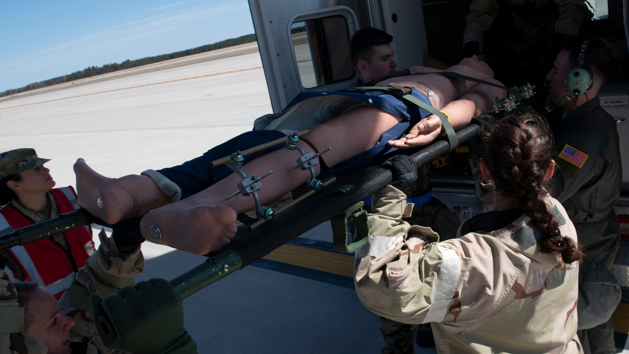 A 60th Aeromedical Evacuation Squadron aircrew and a 60th Medical Group En Route Patient Staging System (ERPSS) team from Travis Air Force Base, California, lift a simulated patient into an ambulance at the Alpena Combat Readiness Training Center, Alpena, Michigan, April 12, 2022.