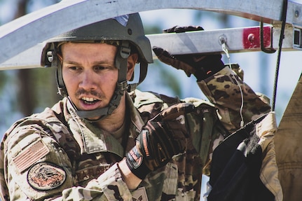 A U.S. Air Force Airman attaches a hook to aid in securing the frame of an Alaskan Small Shelter System at the Silver Flag exercise on Tyndall Air Force Base, Florida, March 31, 2022. The primary focus of Silver Flag is to teach Airmen from the civil engineer, force support, and vehicle maintenance squadrons essential skills to complete operations outside of their primary duties.