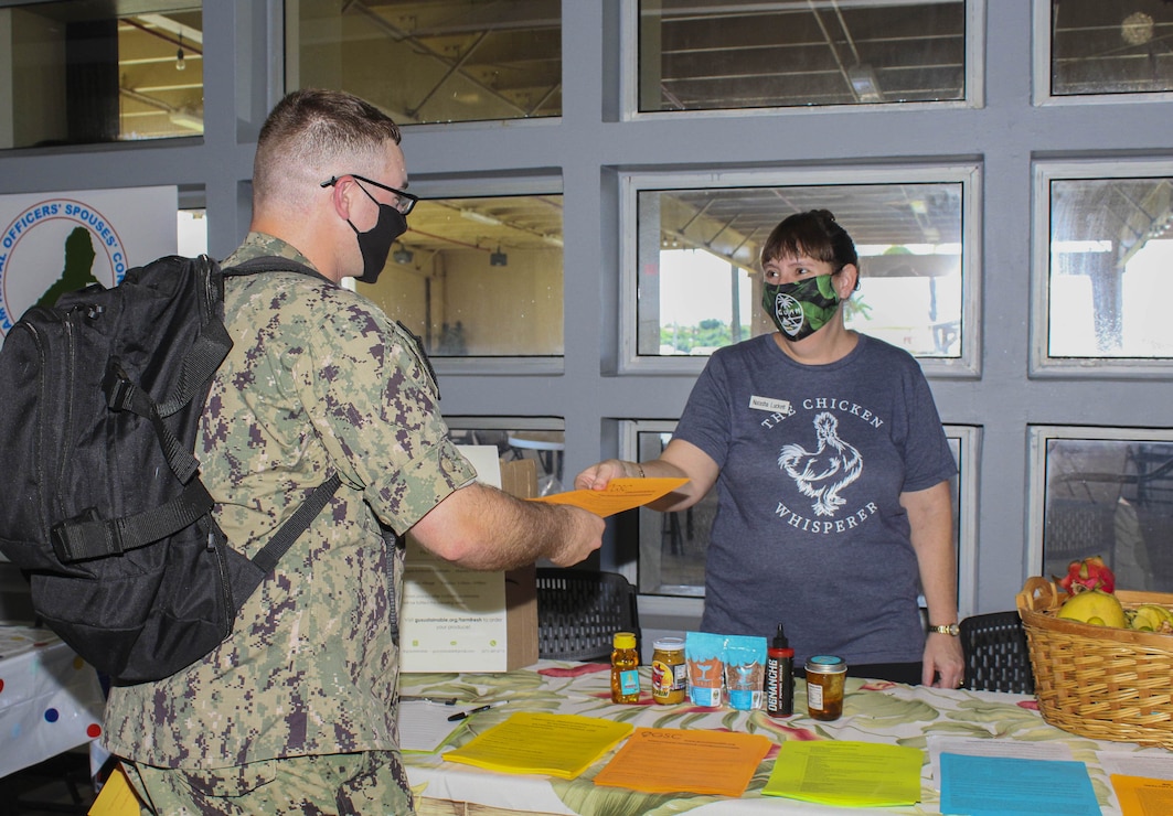 Natasha Luckett hands a packet of information to an incoming Sailor at a resource fair held onboard U.S. Naval Base Guam (NBG) Sept. 30.