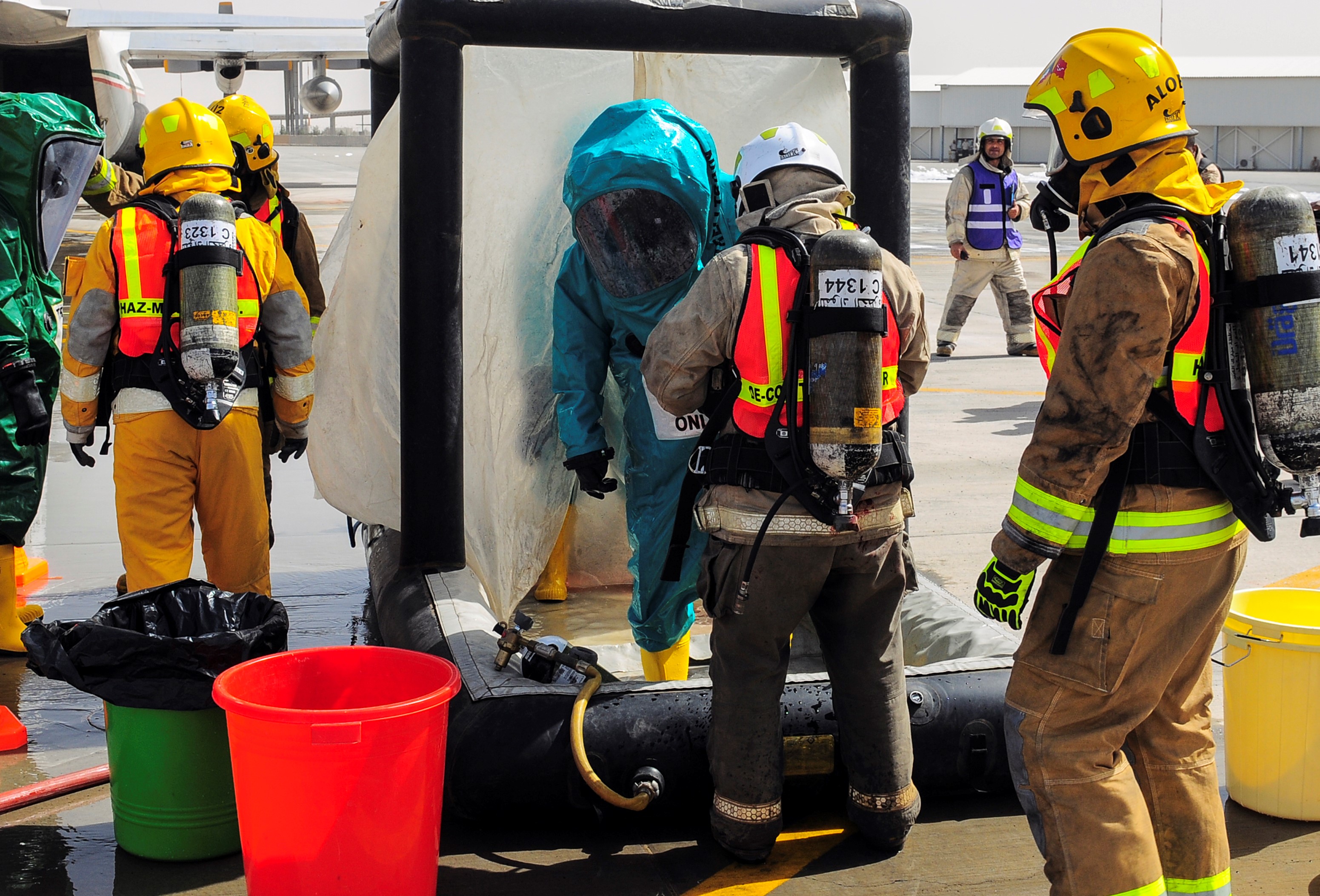 Marines in bright hazmat suits practicing a decontamination.