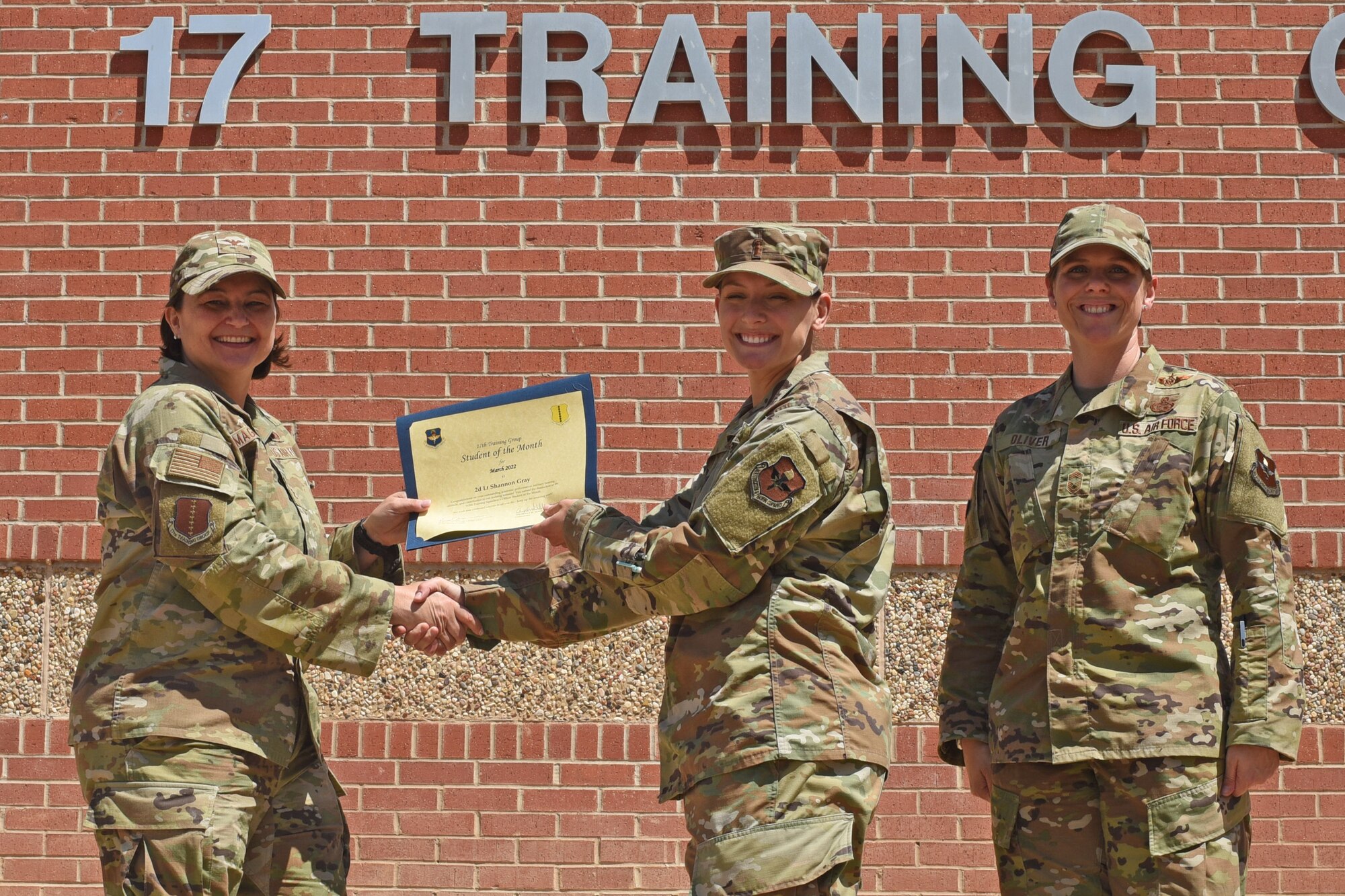 U.S. Air Force Col. Angelina Maguinness, 17th Training Group commander, and Chief Master Sgt. Breana Oliver, 17th TRG superintendent, present 2nd Lt. Shannon Gray, 315th Training Squadron student, the 17th TRG Student of the Month award for March 2022, Goodfellow Air Force Base, Texas, April 15, 2022. The 315th TRS’s mission is to train, educate and inspire the future intelligence, surveillance and reconnaissance warriors. (U.S. Air Force photo by Senior Airman Abbey Rieves)