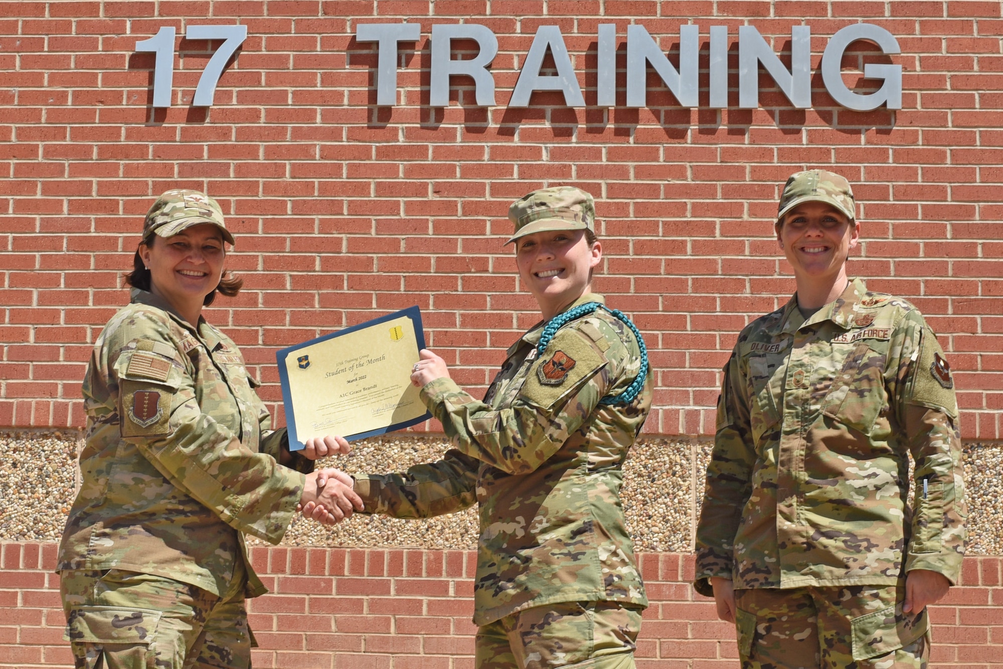 U.S. Air Force Col. Angelina Maguinness, 17th Training Group commander, and Chief Master Sgt. Breana Oliver, 17th TRG superintendent, present Airman 1st Class Grace Brandt, 17th TRG student, a 17th TRG Student of the Month award for March 2022, Goodfellow Air Force Base, Texas, April 15, 2022. Brandt worked hard for her award and has shown her dedication to her squadron and the training she received at Goodfellow. (U.S. Air Force photo by Senior Airman Abbey Rieves)