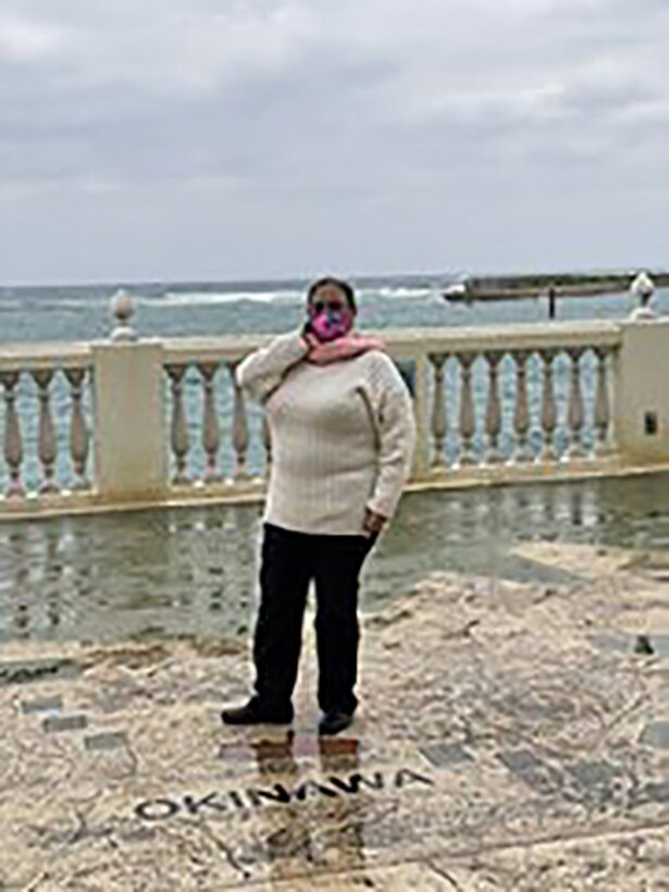 A woman poses in front of the ocean.
