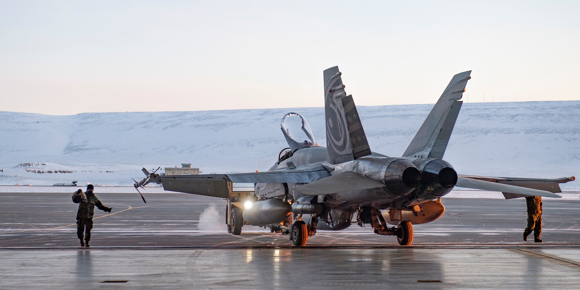 A servicemember guides a Royal Canadian Air Force CF-18 Hornet into the hangar upon arrival at Thule Air Base, Greenland, for Operation NOBLE DEFENDER, March 14, 2022.