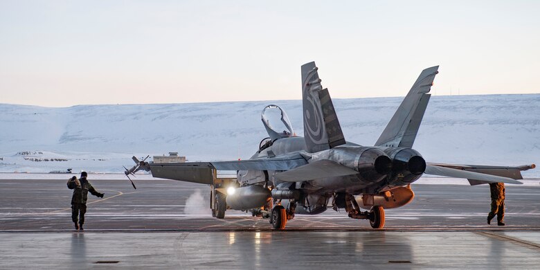 A servicemember guides a Royal Canadian Air Force CF-18 Hornet into the hangar upon arrival at Thule Air Base, Greenland, for Operation NOBLE DEFENDER, March 14, 2022.