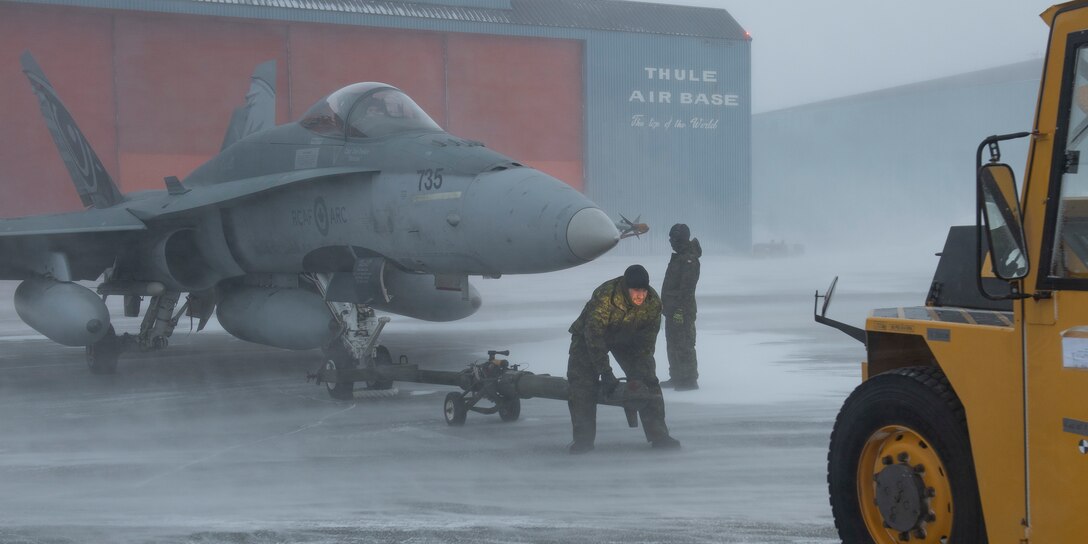 Royal Canadian Air Force crew chiefs conduct towing procedures for a CF-18 Hornet during Operation NOBLE DEFENDER at Thule Air Base, Greenland, March 16, 2022.