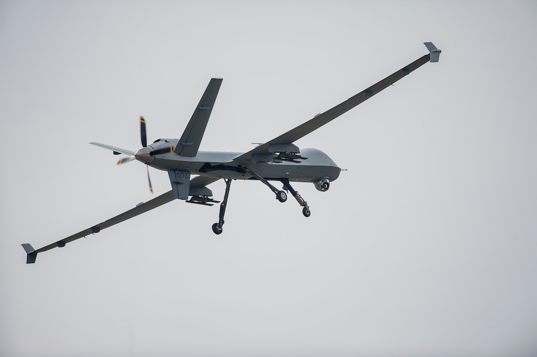 A MQ-9 Reaper drone flys across a grey sky.